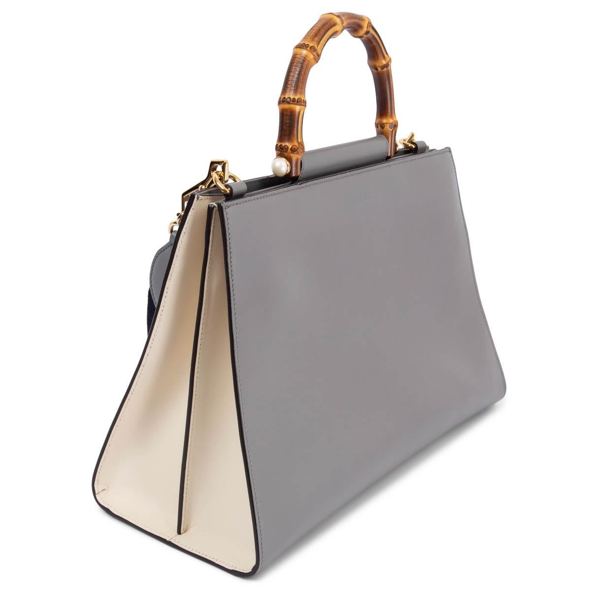 Este bolso de hombro de asa superior Gucci Nymphaea Bamboo 100% auténtico en piel de becerro lisa gris está acentuado con herrajes en tono dorado y la bandolera de rayas Web característica de la casa. Se abre con dos botones magnéticos ocultos en la