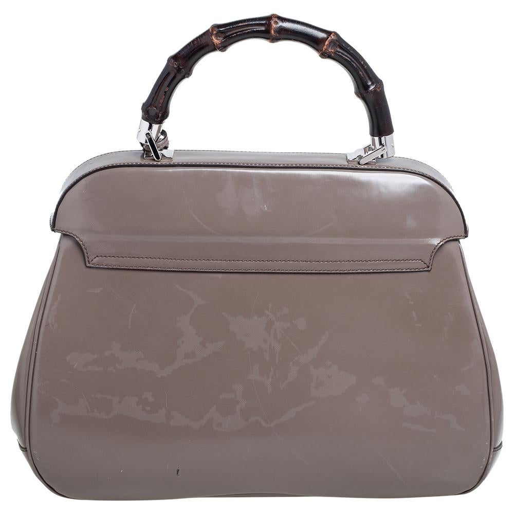 Featuring the iconic Lady Lock, this sophisticated top handle bag is from Gucci. This creation is crafted from leather in a grey shade and features a bamboo top handle. The push-lock closure opens to a leather-lined interior that houses open