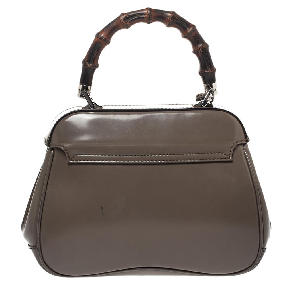 Featuring the iconic Lady Lock, this top handle bag is from Gucci. This bag is crafted from grey-hued leather and features a signature bamboo top handle. The push-lock closure opens to a suede-lined interior that houses an open compartment. Carry