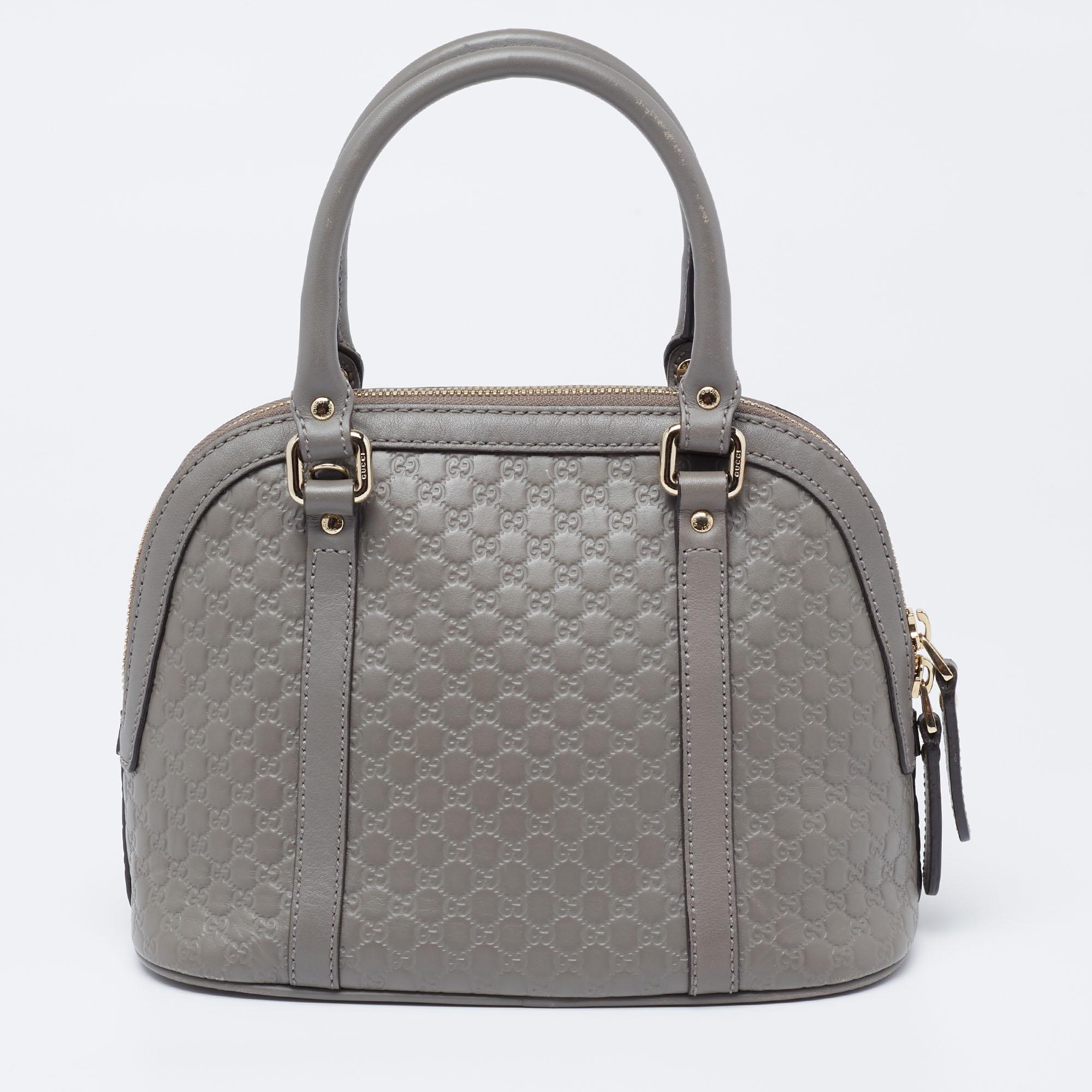 Hold everything you need in style with this mini Dome bag from the house of Gucci. Its grey color exudes a grand appeal, and the Microguccissima leather projects the iconic Gucci charm. The versatility lies in the dual-rolled handles and long