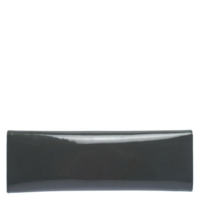 This sleek Sigrid clutch from the house of Gucci is a masterpiece. Crafted in Itlay, it is made of glossy patent leather and comes in a stunning shade of grey. It features a front flap which features delicate silver-tone cutout detailing and the