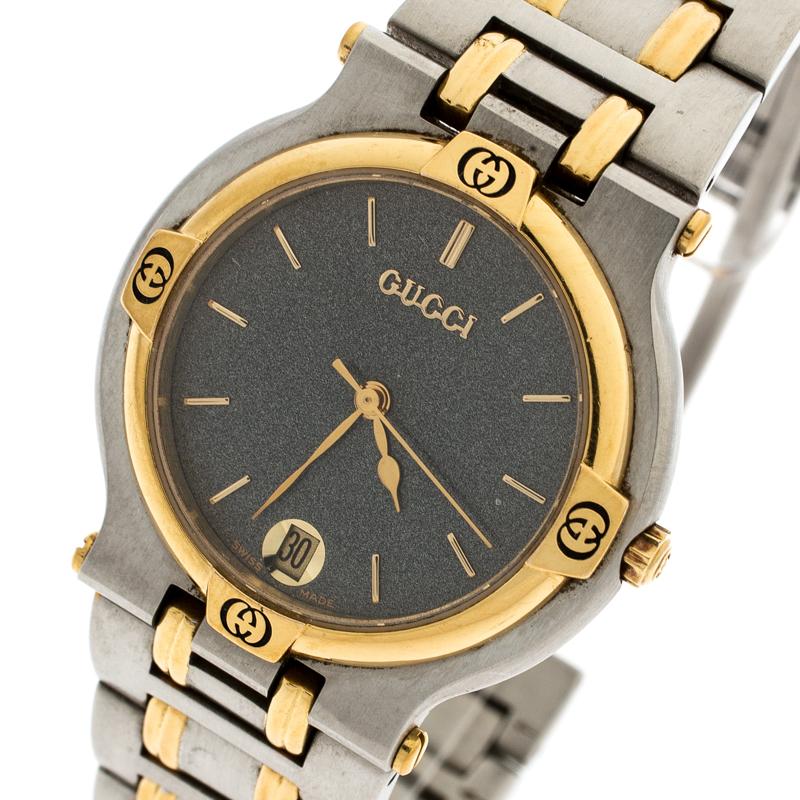 This timepiece from the house of Gucci will beautify your look by adding just the right touch of luxury. Crafted from stainless steel, its case supports a yellow gold-plated bezel with logos. The grey dial houses gold-tone hour indexes, hands, and a