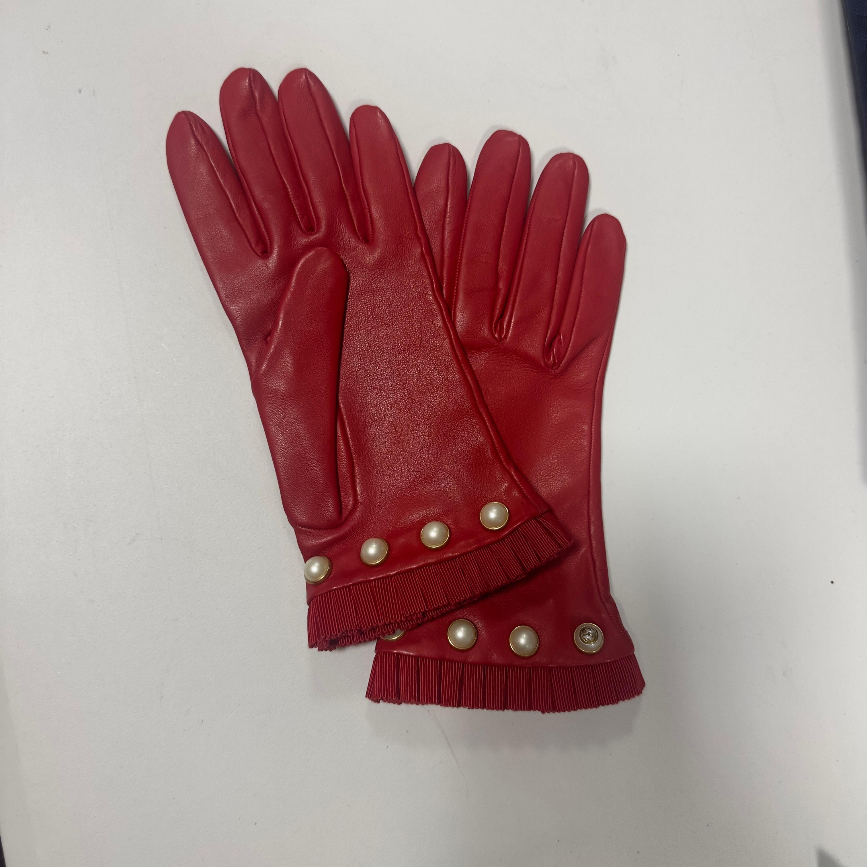 Gucci in morbider roter Pelle, feminin und szenig, mit einer perlenbesetzten Bodenplatte mit verschnörkeltem Profil entlang des Pols. Der Rand ist mit einem eleganten Nastro gros-grain rosso plissé, tono su tono, versehen, das die Hand schmückt und