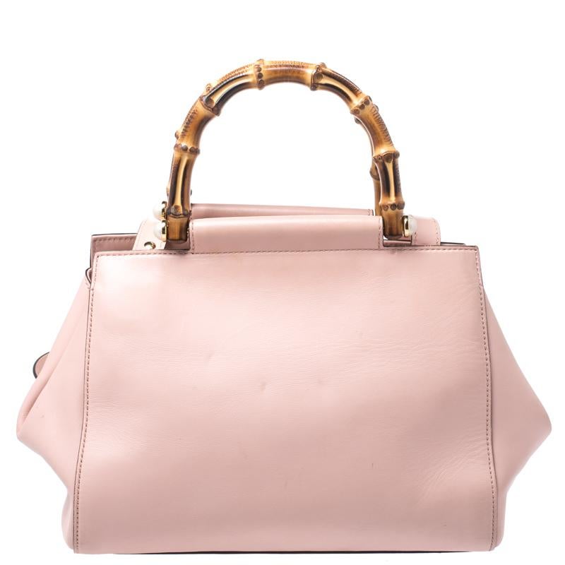 This Gucci bag is an example of contemporary style. Look elegant and fashionable in this chic light pink piece which is styled with bamboo handles featuring pearl details on each side and a shoulder strap. The inside is lined with suede which lends