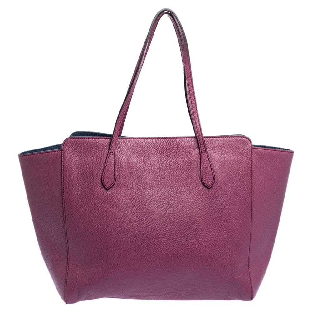 High in appeal and style, this Swing shopper tote is a Gucci creation. It has been crafted from quality leather in Italy and shaped to exude class and luxury. The rose-hued bag comes with two handles, a spacious fabric interior, and the brand label