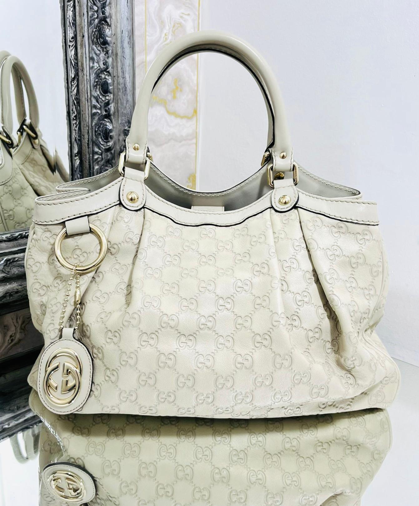 Gucci Guccissima GG Sukey Leather Bag

Ivory tote bag designed with GG monogram embossed.

Featuring dual top rolled handles and magnetic closure.

Detailed with gold GG logo leather detachable charm.

Magnetic corners and black logo interior with