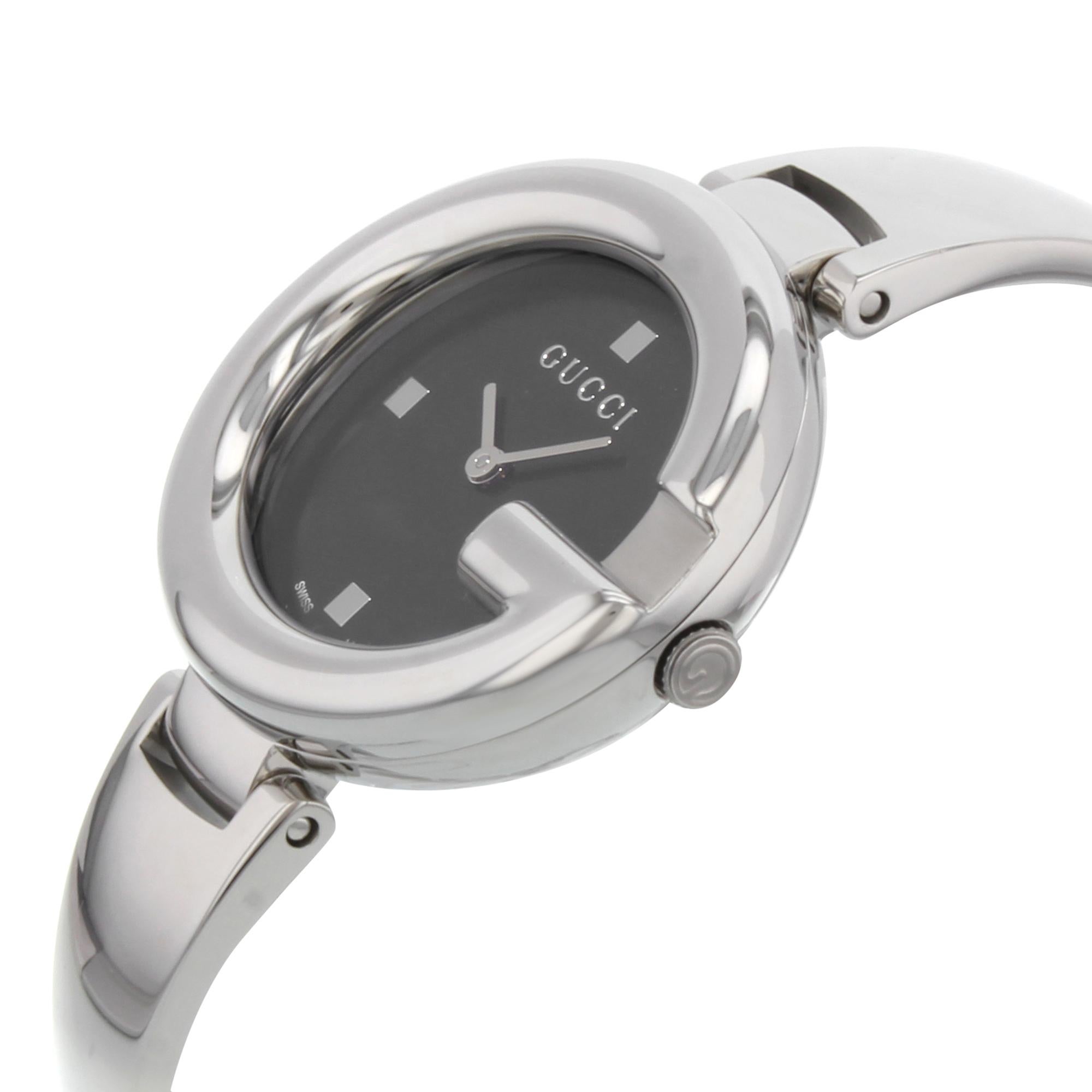 This display model Gucci Guccissima  YA134301  is a beautiful Ladie's timepiece that is powered by quartz (battery) movement which is cased in a stainless steel case. It has a oval shape face, no features dial and has hand dots style markers. It is