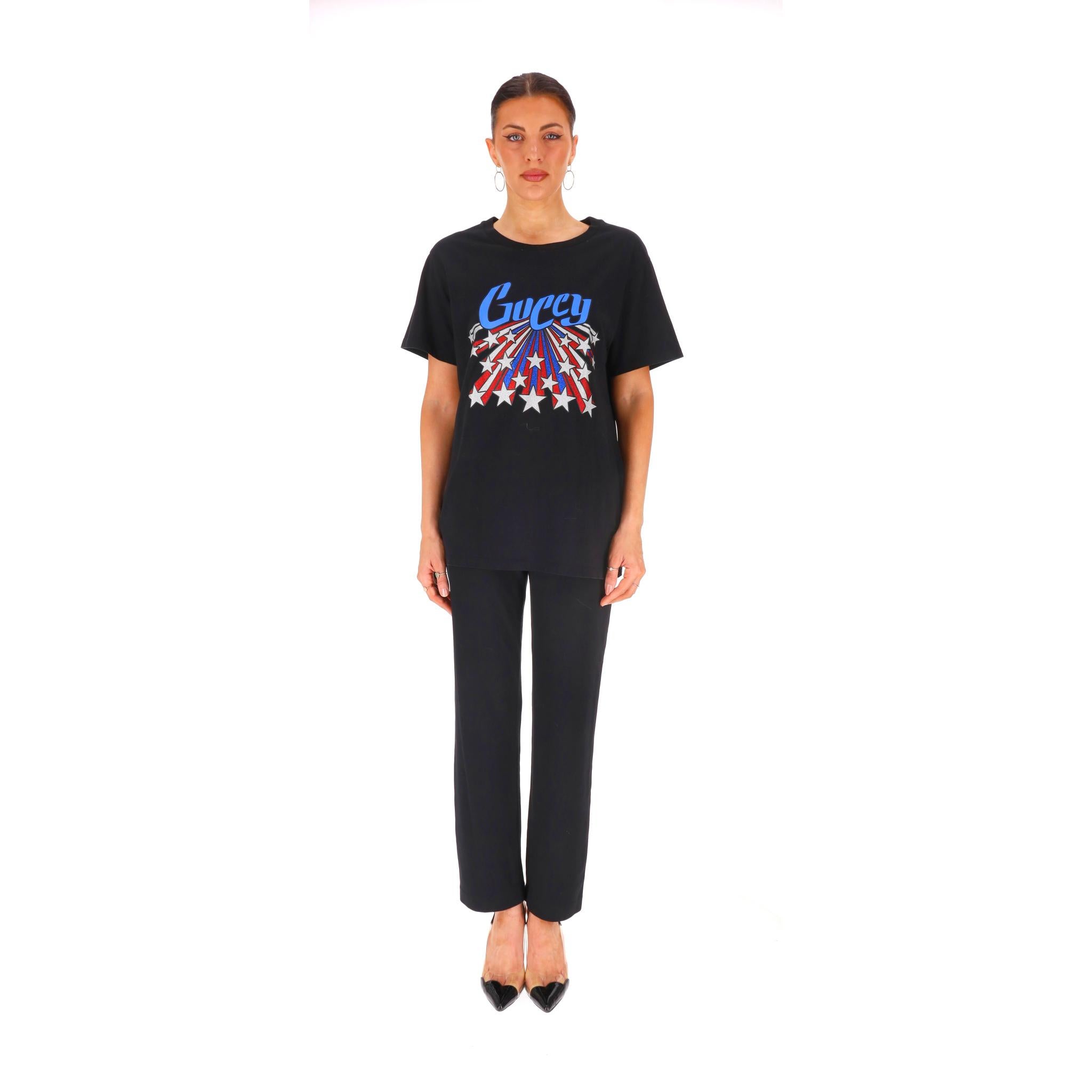 Gucci 'Guccy' Logo Cotton T-Shirt

Black cotton top with a retro-inspired 'Guccy' logo, first introduced in 2018 and dynamic burst of stars designed in the colours of an American flag.

Featuring round neckline and short sleeves.

Rrp Approx.