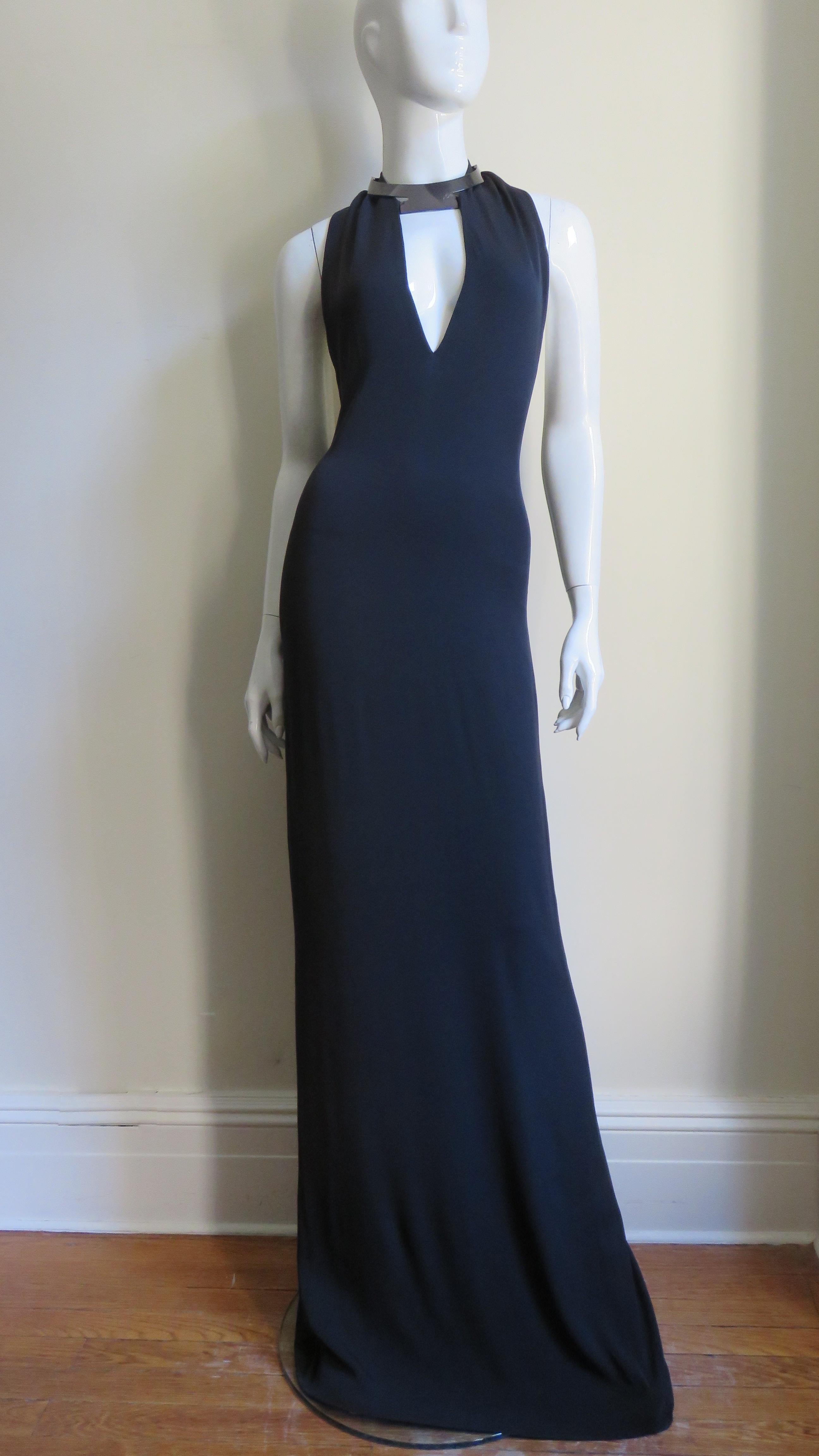 A gorgeous elegant black silk dress from Gucci S/S 2010 collection. The halter style dress has a front plunging cut out below a fabulous silver grey choker style collar with adjustable leather straps closing at the back of the neck. The dress skims