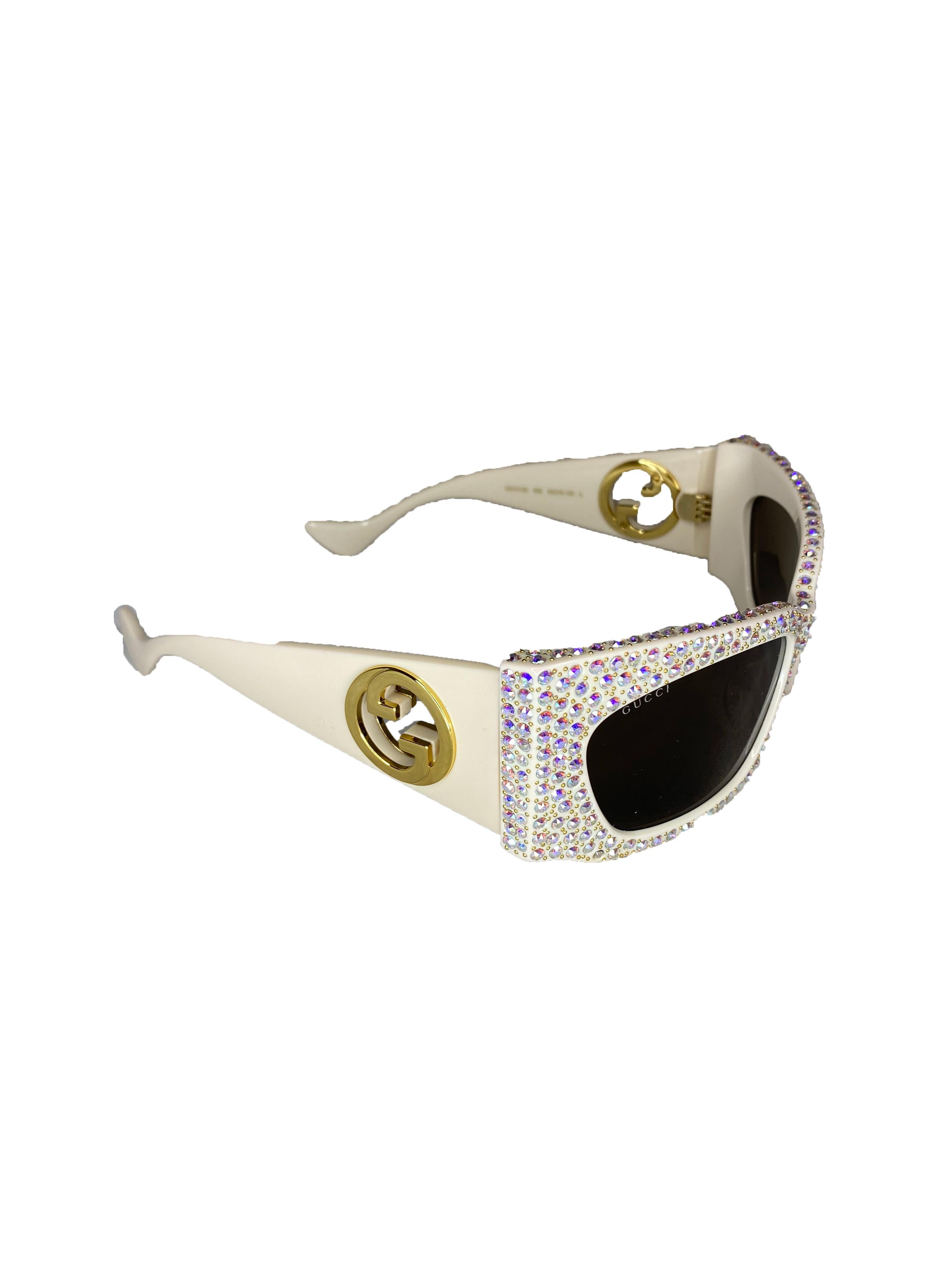 From the Hollywood Forever Collection, crystal embellished sunglasses from Gucci. Ivory coloured acetate frame with hand applied iridescent crystals. Rectangular shape. Tinted lenses. Gold coloured side logo. 100% UVA/UVB protection. Model No:
