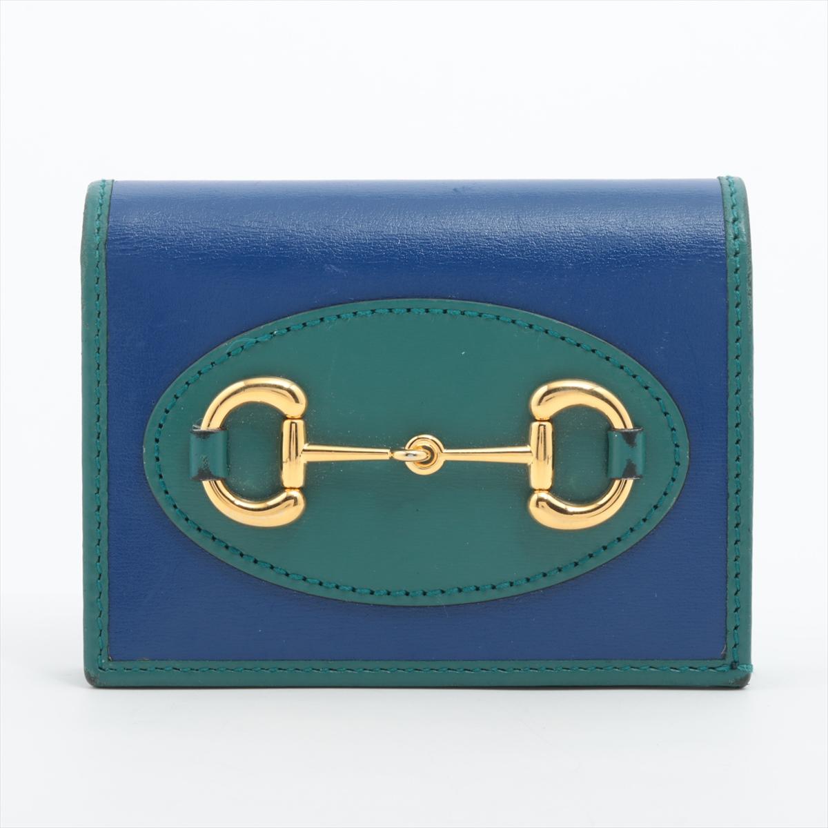 The Gucci Horse Bits Leather Compact Wallet in Blue and Green is a stylish and compact accessory that effortlessly blends luxury with vibrant colors. Crafted from high-quality leather, the wallet features the iconic horse-bite motif, showcasing