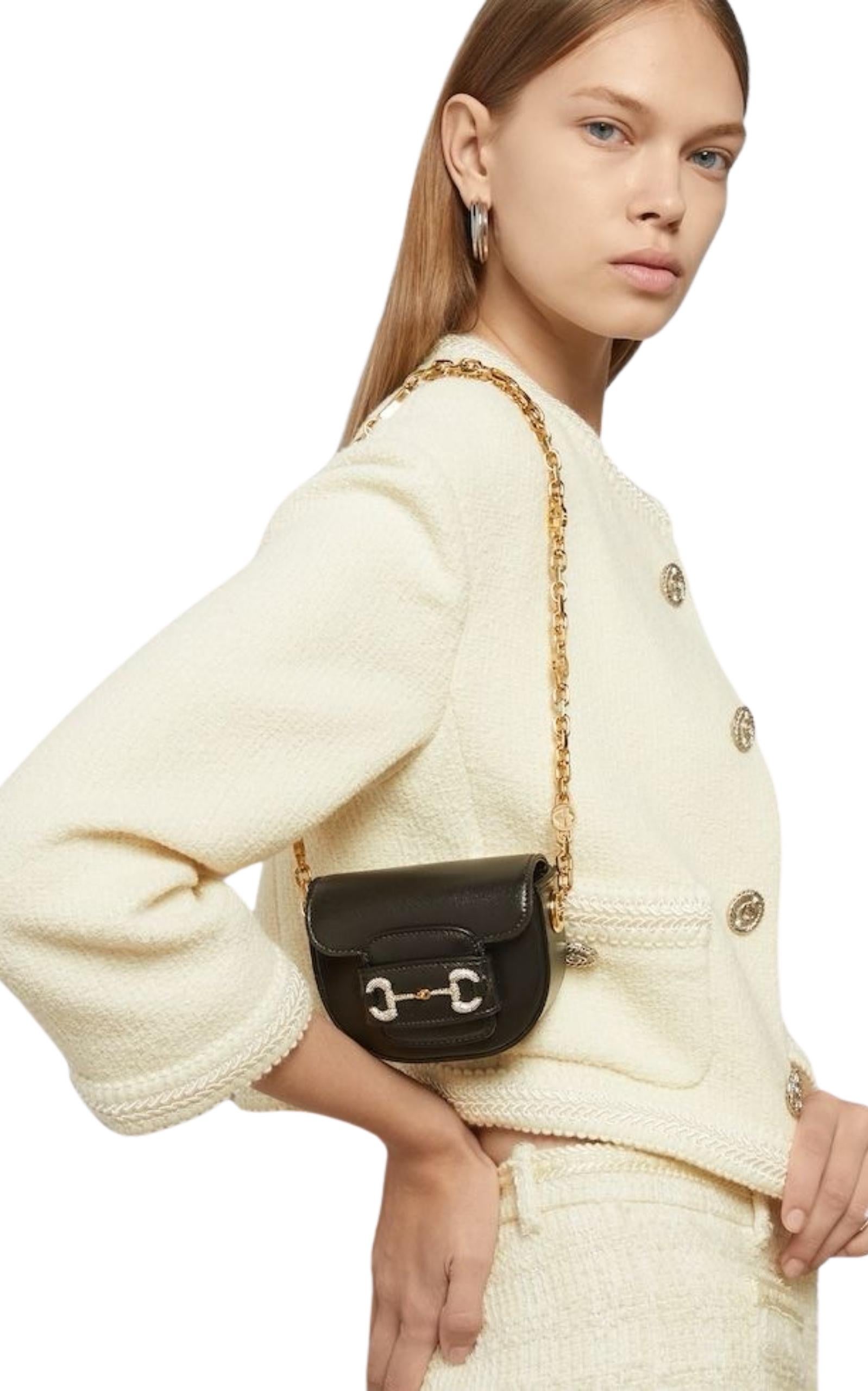 Black ‘Horsebit 1955’ belt bag from Gucci. 
Made from calf leather, this design secures with a sliding fastener and showcases the brand's signature horsebit bejewelled with sparkling crystals. It is complete with a detachable chain strap with