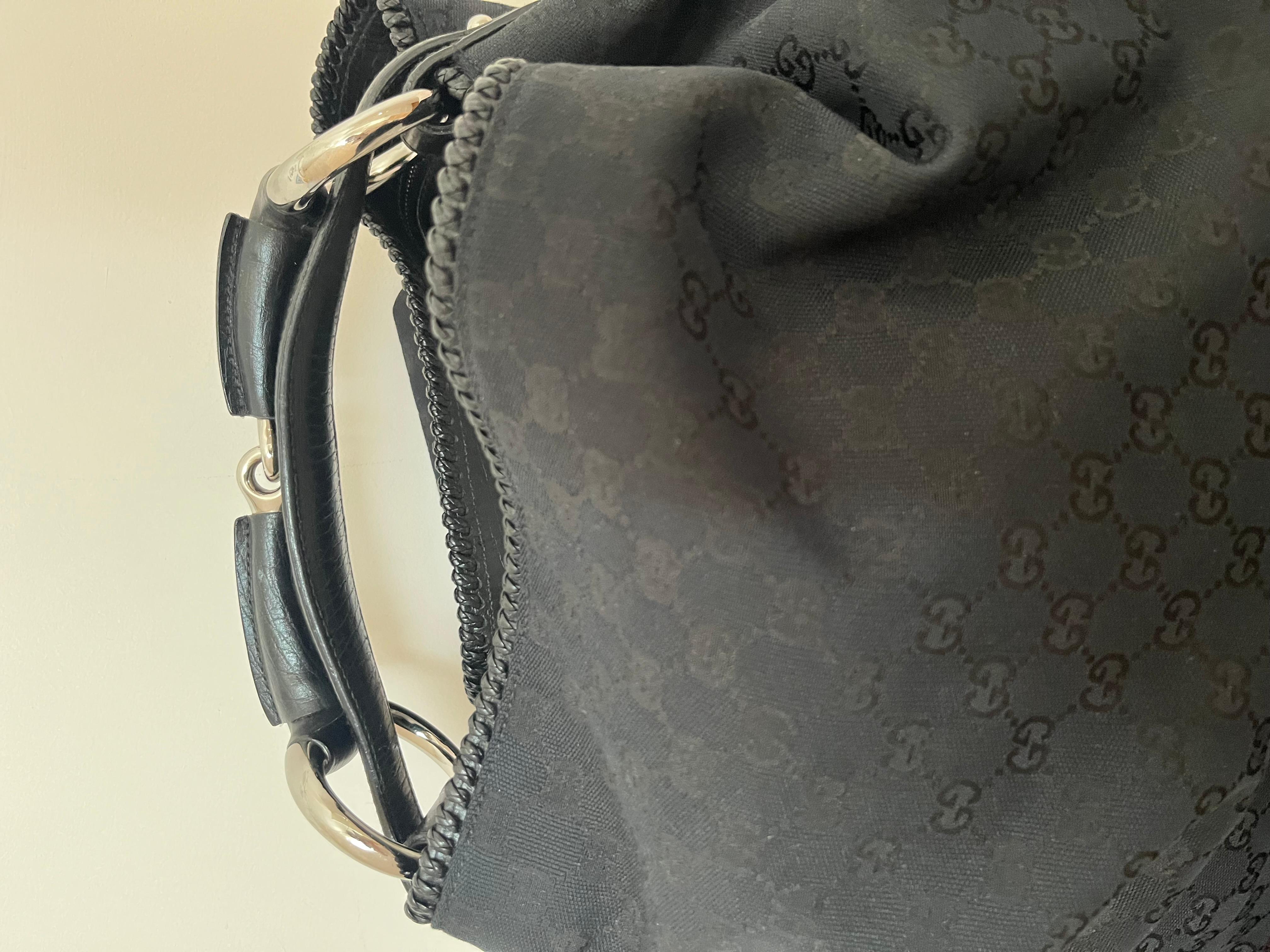 Substantial Gucci Horsebit Canvas and Leather Hobo Bag with intricate handle.

The best feature of this hobo bag is the looping shoulder strap and polished silver hardware. This includes a wrapped horsebit metal embellishment.

This canvas and