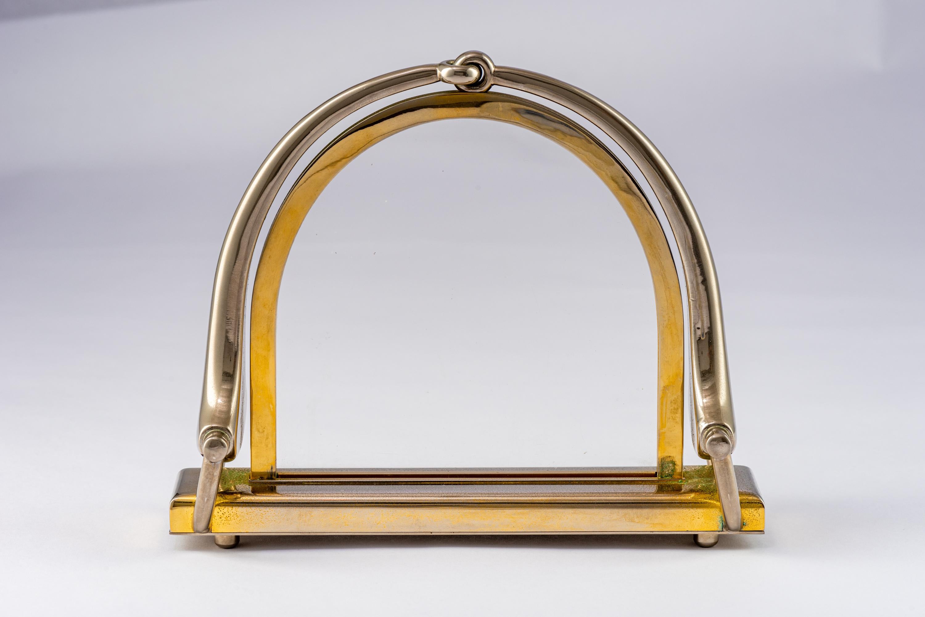 Gucci Horsebit picture frame, brass, nickel, signed. Stirrup form photo frame finished in brass and nickel. The display opening is 5.63 inches in height by 5.75 inches wide. The four circular feet on the underside of the base unscrew, releasing the