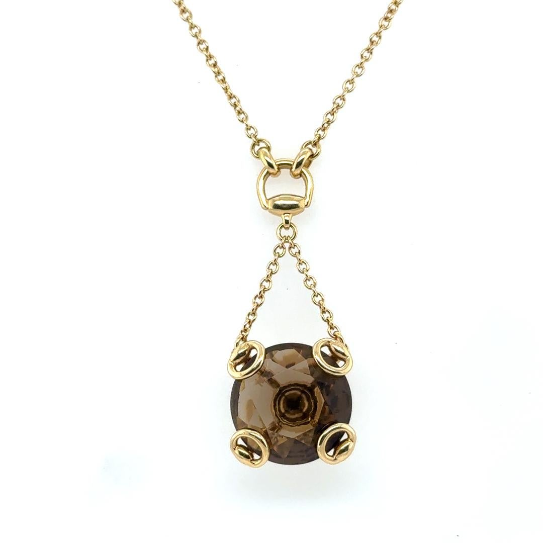 Magnifique collier du célèbre designer Gucci. Le collier est réalisé en or jaune 18 carats et met en valeur une pierre précieuse en quartz fumé de taille ronde. Le collier met en valeur le design iconique du mors de cheval de Gucci, que l'on