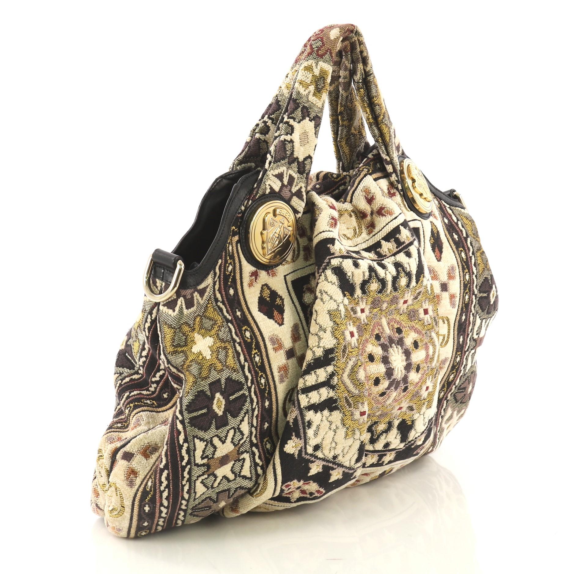 This Gucci Hysteria Convertible Top Handle Bag Tapestry Medium, crafted from multicolor tapestry, features dual shoulder straps with Gucci emblems, pleated silhouette, and gold-tone hardware. Its magnetic snap closure opens to a black fabric