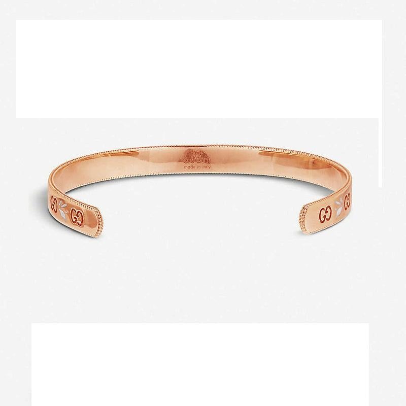 This gorgeous Gucci Icon cuff bangle is professionally crafted in 18ct Rose Gold. It features the iconic Gucci double 'G' motif, and is embellished with white enamel blossom detailing. Around the edge, the bangle, milgrain detailing adds to the