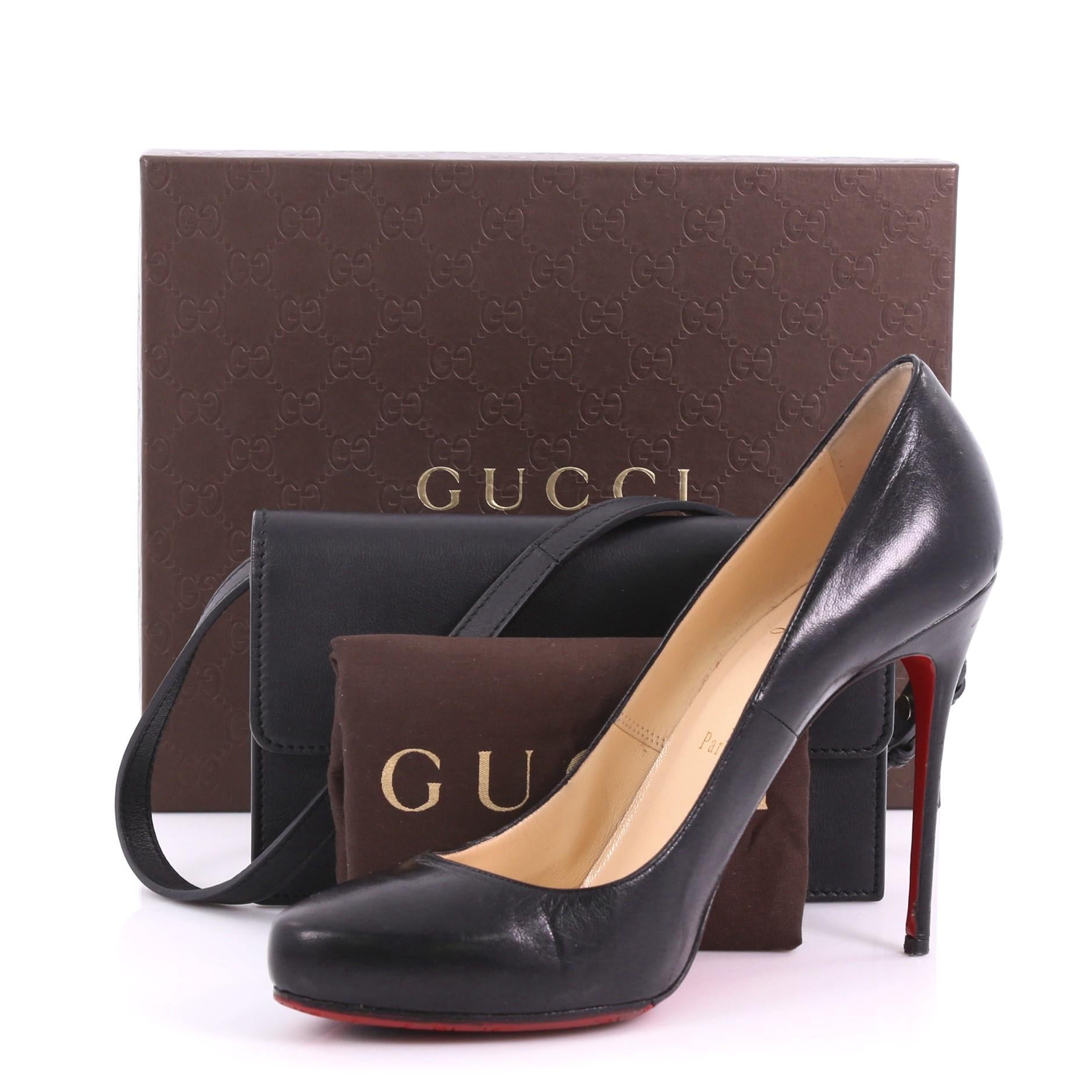 This Gucci Icon Wallet on Strap Leather, crafted from black leather, features adjustable shoulder strap, interlocking GG snap closure and gold-tone hardware. Its flap opens to a black leather interior with multiple card slots, and zip pocket.