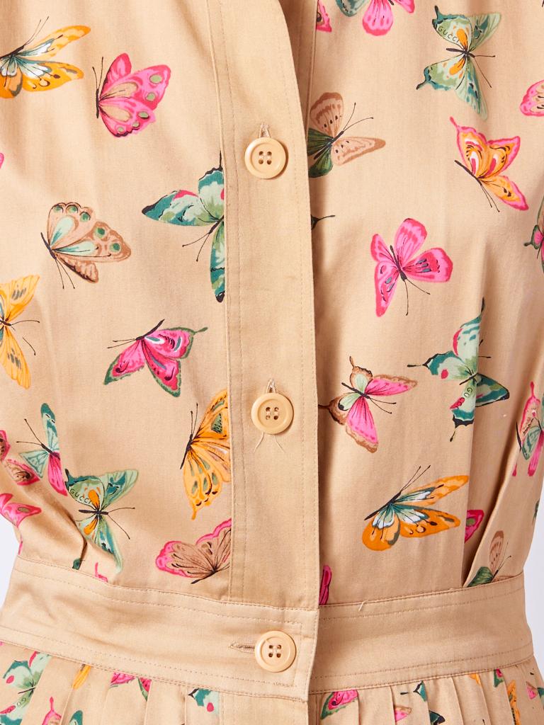 Gucci, multi tone,  iconic, butterfly pattern on a khaki ground, cotton, shirt dress, having a short set in sleeve, pointed, small collar, and button closures going down the center front.. Dress gathers at the waist.