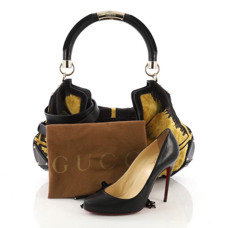 This Gucci Indy Hobo Velvet Tapestry Medium, crafted from black and yellow tapestry, features tassels with bamboo hardware accents, leather plated base edges, looped handle, and gold-tone hardware. It opens to a black fabric interior with side zip