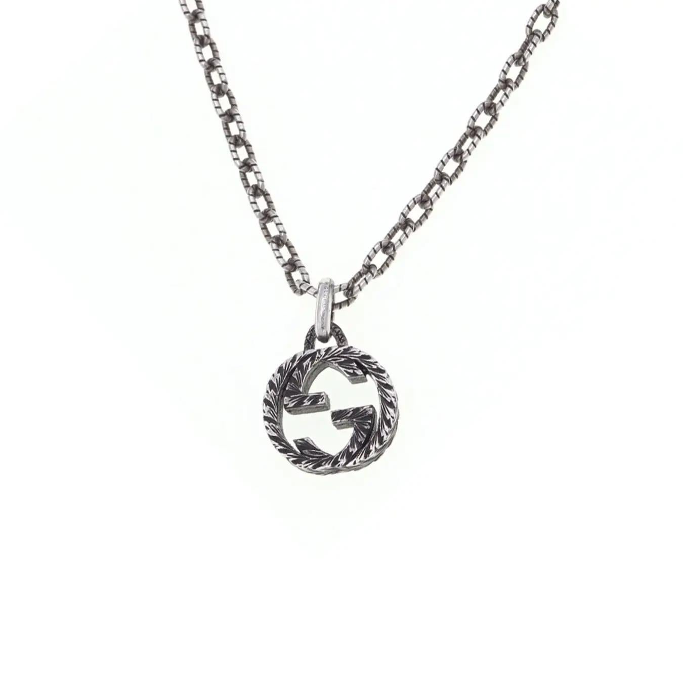 This GUCCI necklace features a textured chain with an interlocking G pendant in an engraved pattern. Designed in 925 sterling silver. Secured with lobster clasp. Chain length: 17.5 inches. Pendant size: 16.7mm x 15mm. Made in Italy. Unworn