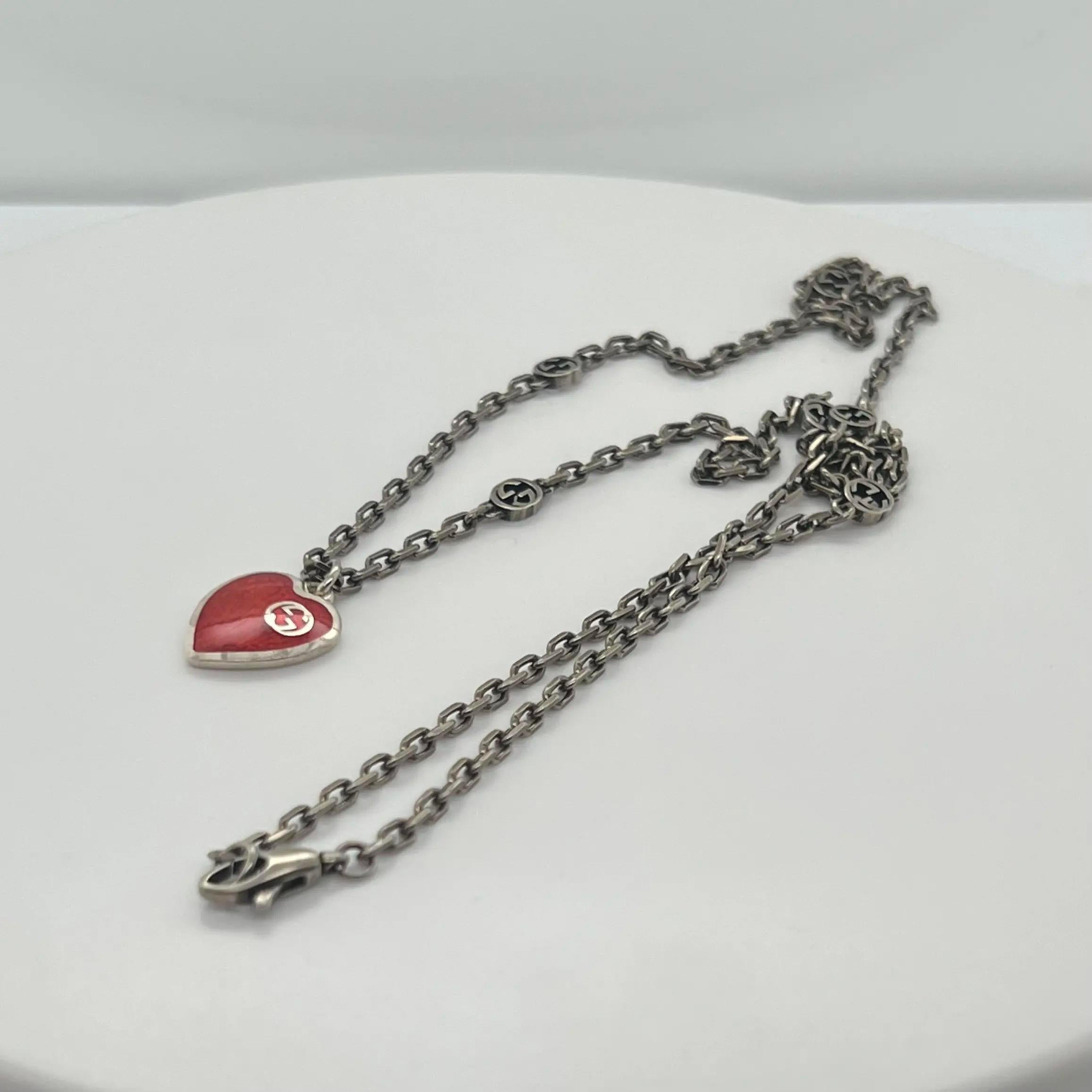 This Beautiful GUCCI necklace is imbued throughout with the emblematic Interlocking G motif with an engraved heart pendant animated by red enamel. Designed in 925 sterling silver with semi shiny finished chain. Secured with a lobster lock. Chain