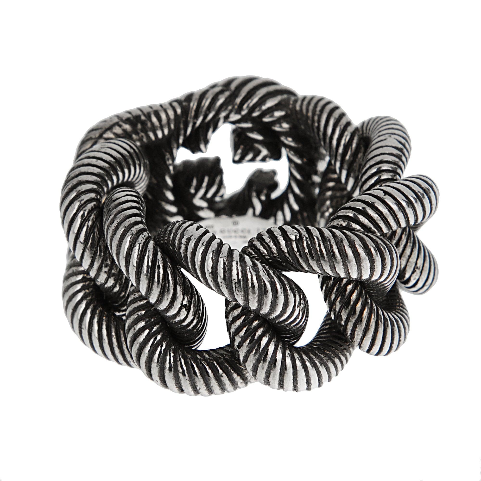Un anello in argento Gucci, realizzato in argento 925 invecchiato. Presenta maglie in corda intrecciata che formano una silhouette audace e dimensionale, ricca di dettagli. Il design integra sottilmente il logo G intrecciato di Gucci, che emerge