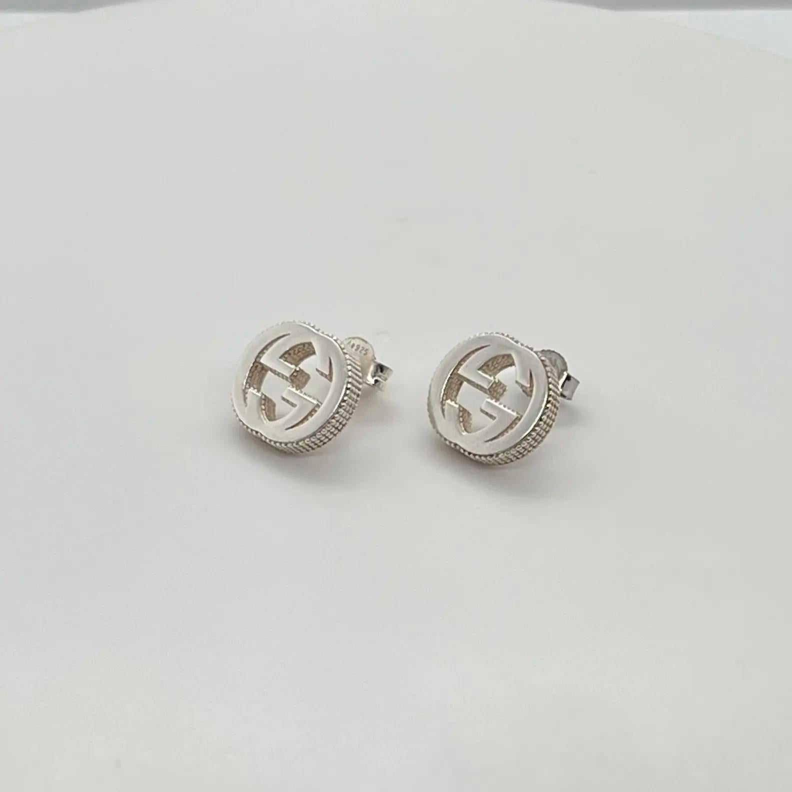 These gorgeous GUCCI interlocking G stud earrings are designed in 925 sterling silver with a textured outline. Earring size: 11.5mm x 12.7mm. Total weight: 5.45 grams. Comes with one Gucci stamped push back closure and one regular silver pushback.
