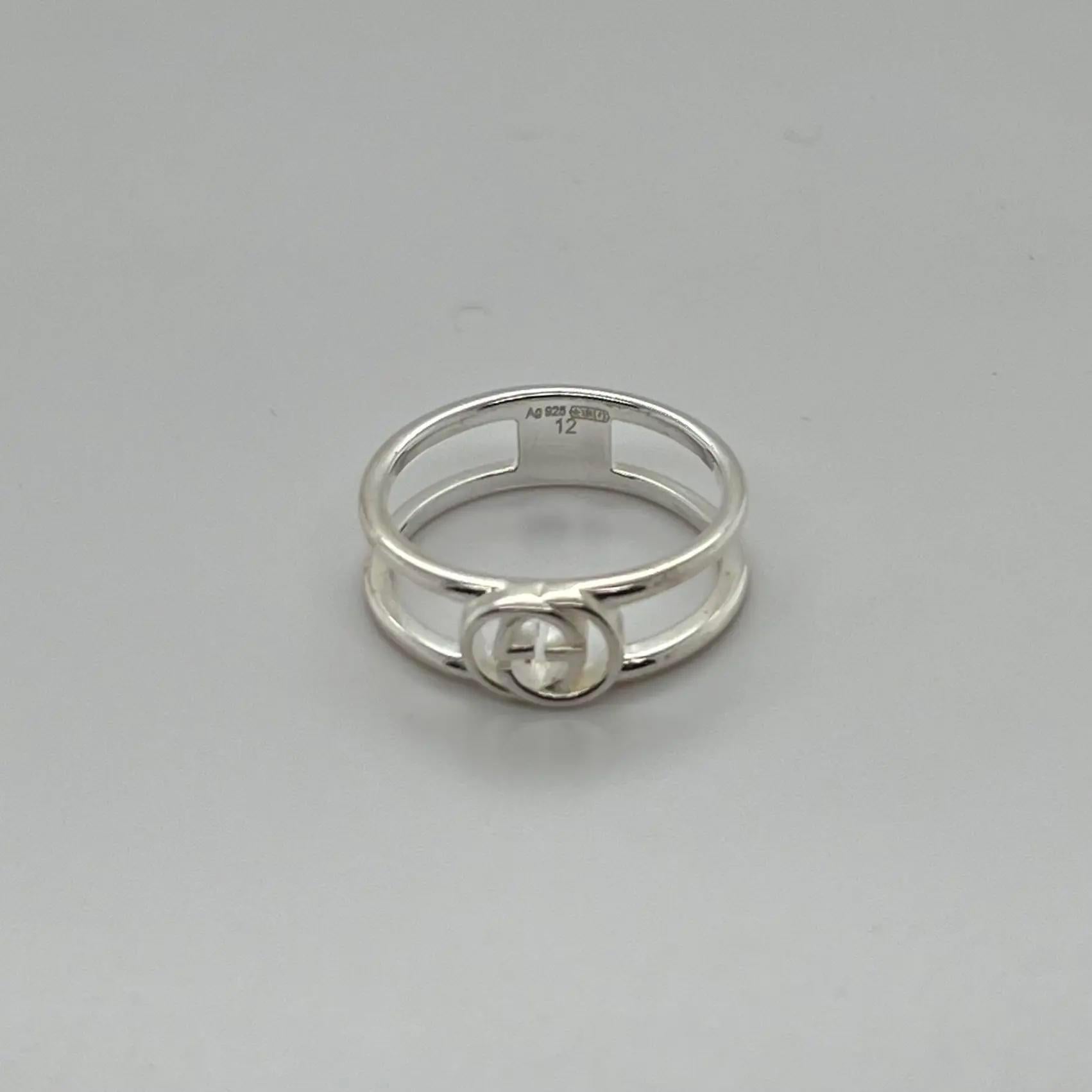 This GUCCI interlocking G thin band ring is designed in 925 sterling silver. Featuring two bands connected by Guccio Gucci's monogram in the center. Ring size: 12 US 6. Ring width: 5.9mm. Total weight: 2.65 grams. Made in Italy. Unworn condition.