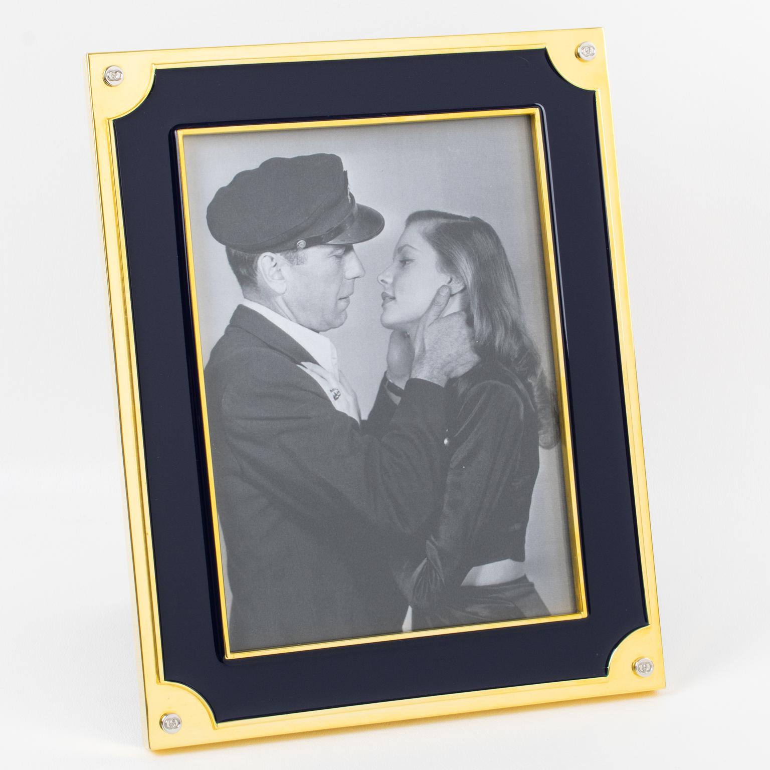 The Italian Fashion House Gucci crafted this luxury enamel and 24K gold plated picture photo frame. The polished gold-plated metal framing is topped with navy blue enamel. The back and easel are made with high gloss walnut wood. The frame is marked
