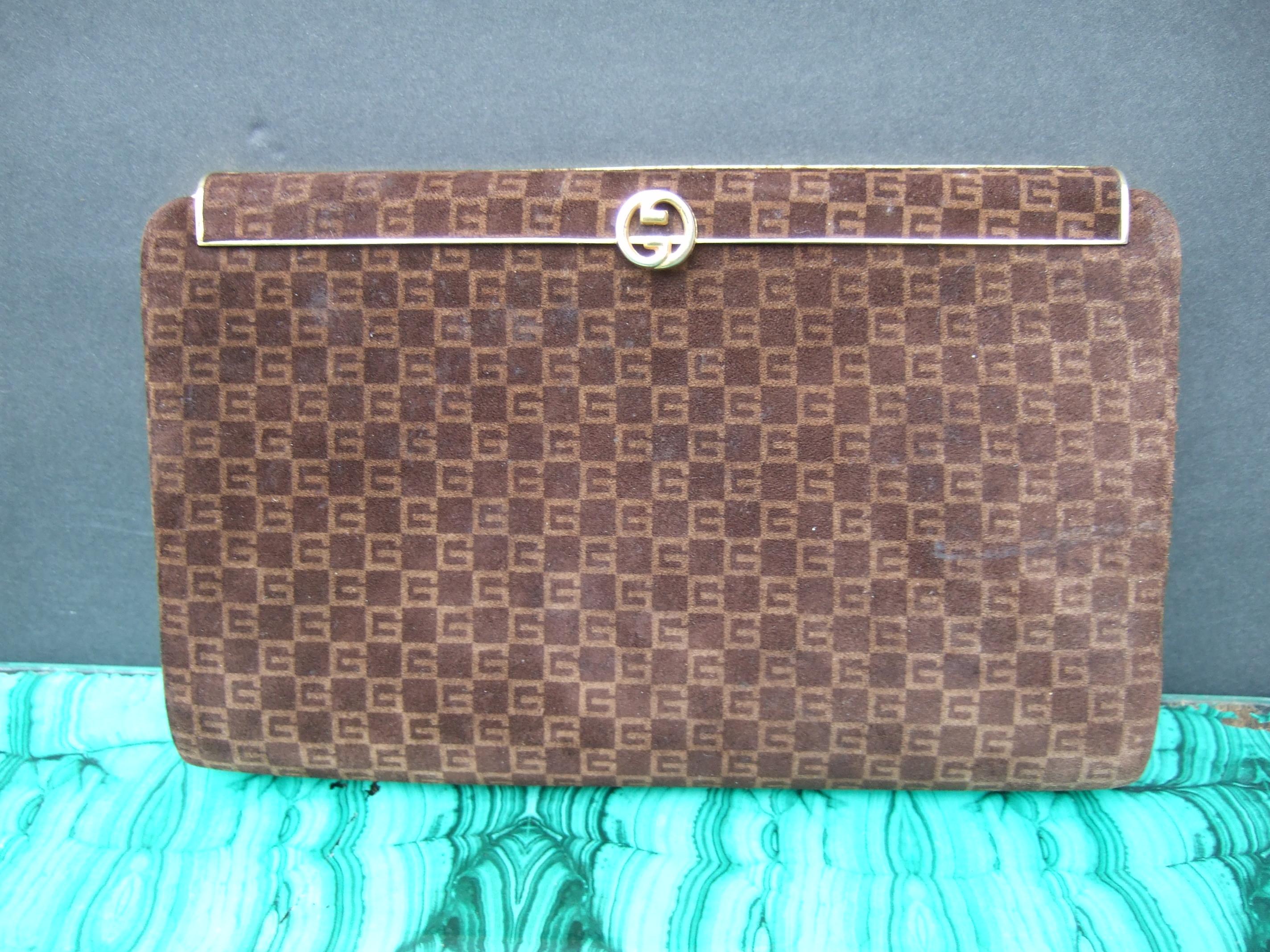 GUCCI Italy Chic brown doeskin suede clutch bag c 1970s 
The brown suede covering is designed with Gucci's subtle 
G initials repeated throughout the front and back exterior
sides in a subtle geometric checkerboard pattern

Adorned with a small gilt
