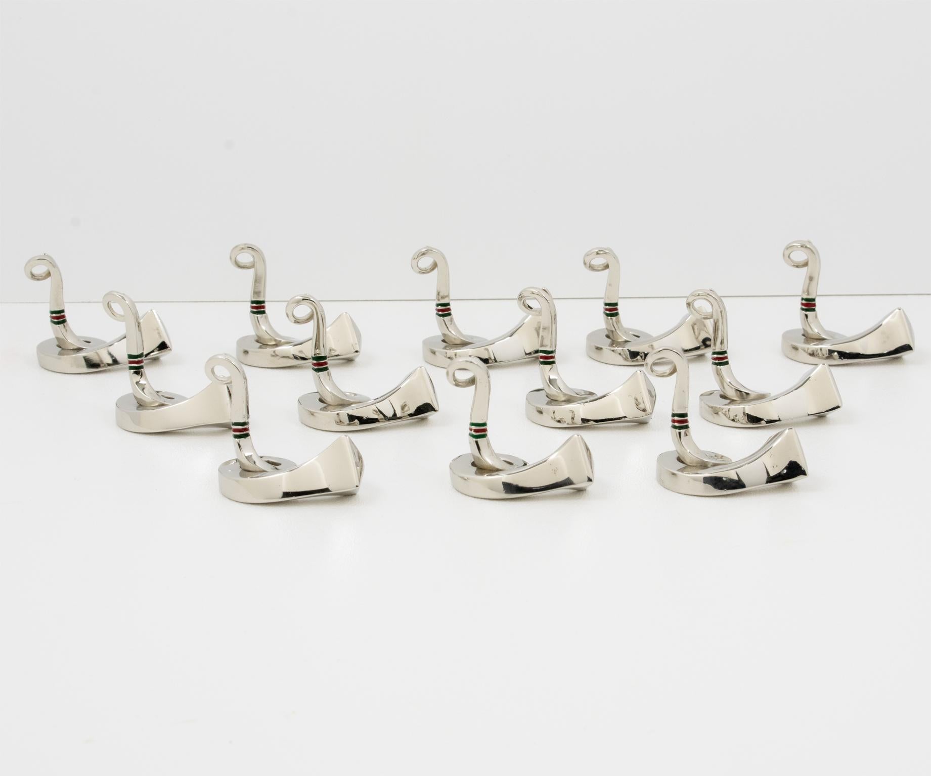 Speisen Sie stilvoll mit diesen skurrilen Tischkartenhaltern aus verchromtem Metall und Emaille, entworfen von Gucci, Italien. Das zwölfteilige Set zeigt ein Reitermotiv mit einem hochglanzverchromten Hufeisennagel oder Hufnagel aus Messing, der zum