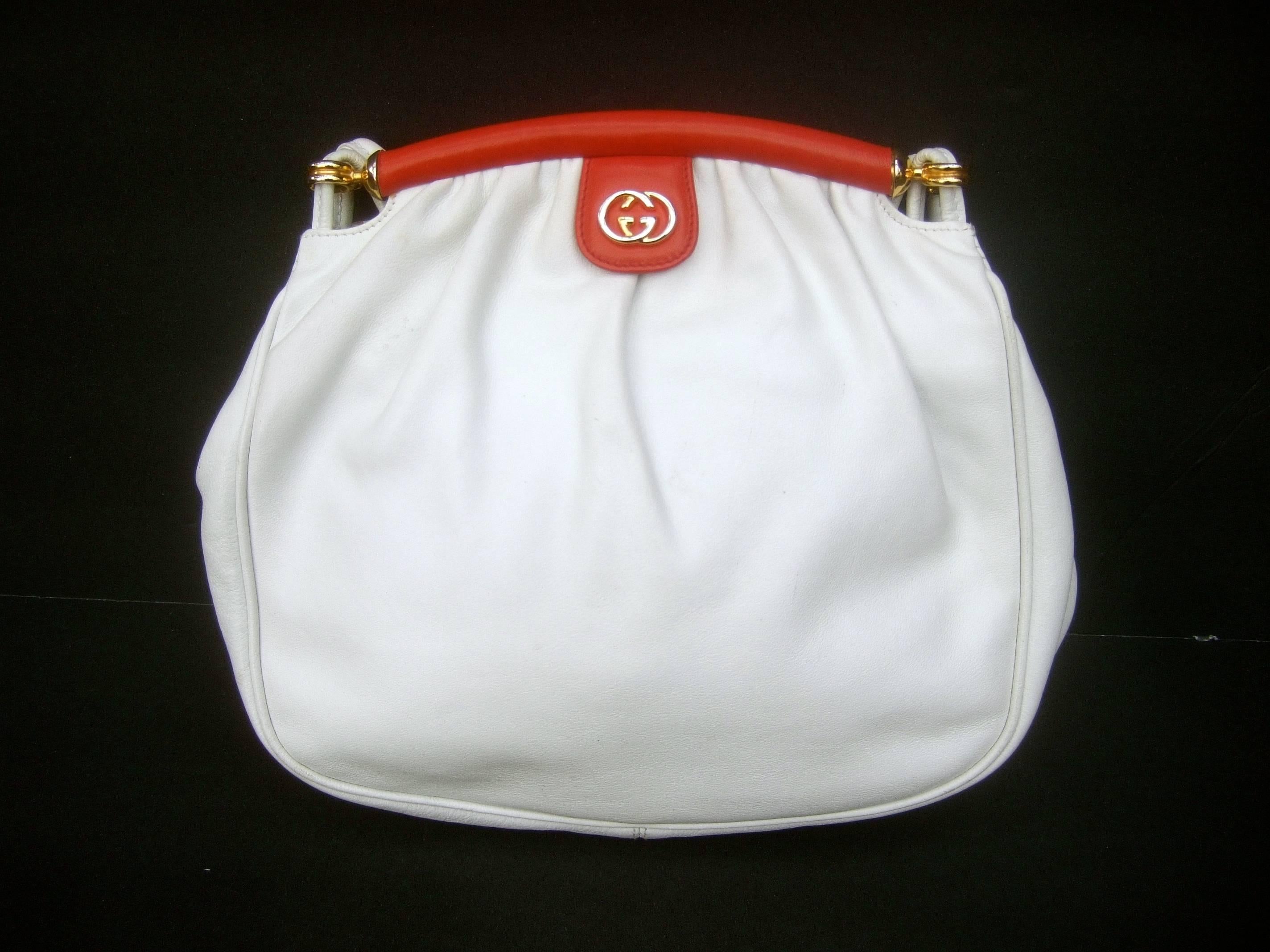 Gucci Italy Crisp white leather versatile shoulder bag c 1980s
The Italian white leather handbag is accented with red
leather that runs across the clasp opening

Gucci's interlocked G.G. initials are adhered to a red 
leather plaque. The versatile