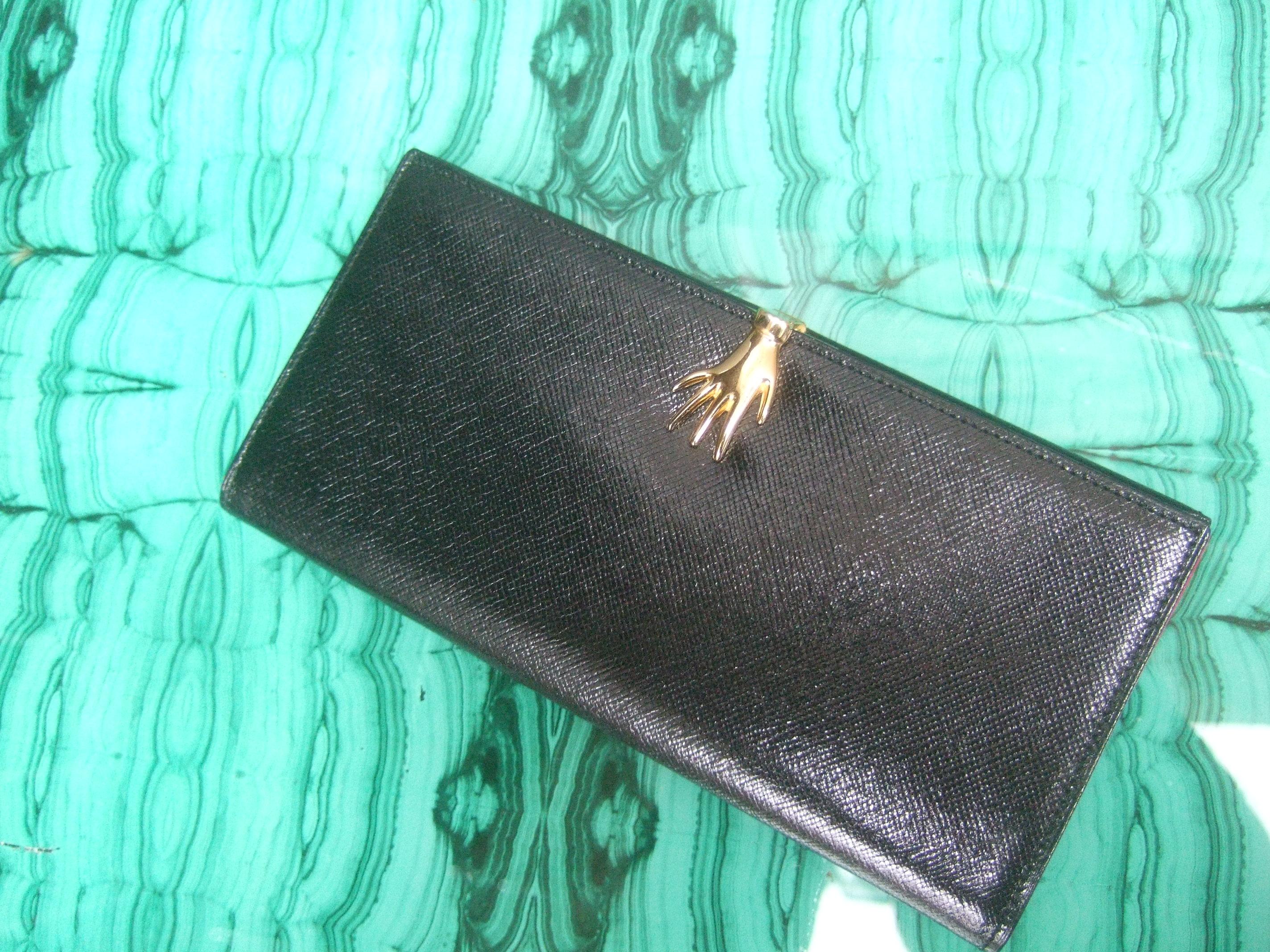 Gucci Italy Rare ebony black leather hand clasp wallet in Gucci presentation box c 1970s
The elegant Italian black leather wallet is designed with a gilt metal hand clasp closure
The cherry red leather interior panels are designed with a pair of