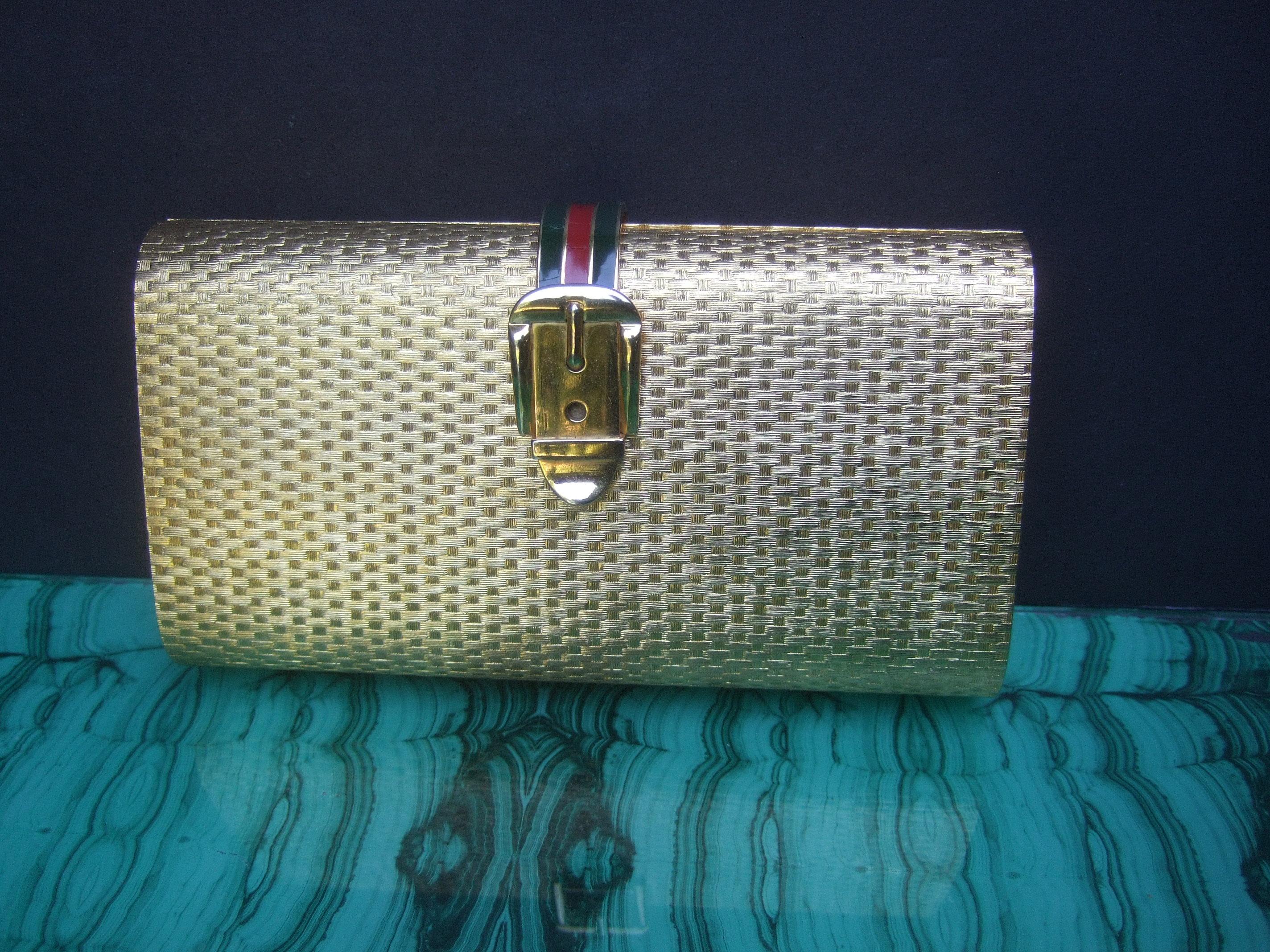 Gucci Italy Rare gilt metal minaudiere' clutch bag c 1970s
The opulent gold metal clutch is designed with a contiguous textured geometric basket weave pattern throughout the exterior

Adorned with a gilt metal buckle clasp emblem; accented with
