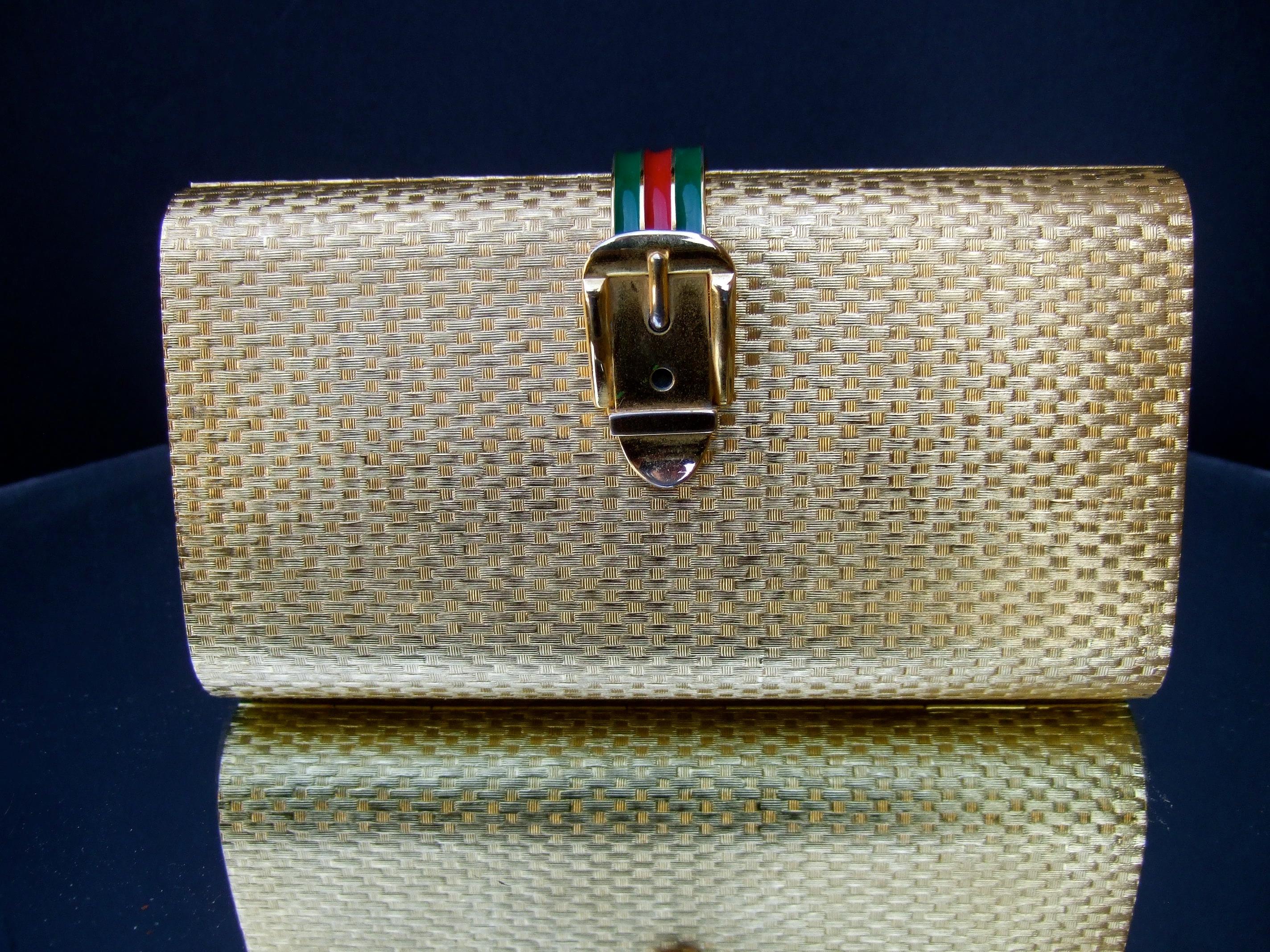 Gucci Italy Opulent rare gilt metal minaudiere' clutch purse c 1970s 
The elegant rectangular clutch is embellished with a criss cross basket weave pattern
on the exterior 

Designed with a hinged clasp band accented with red & green stripes. The