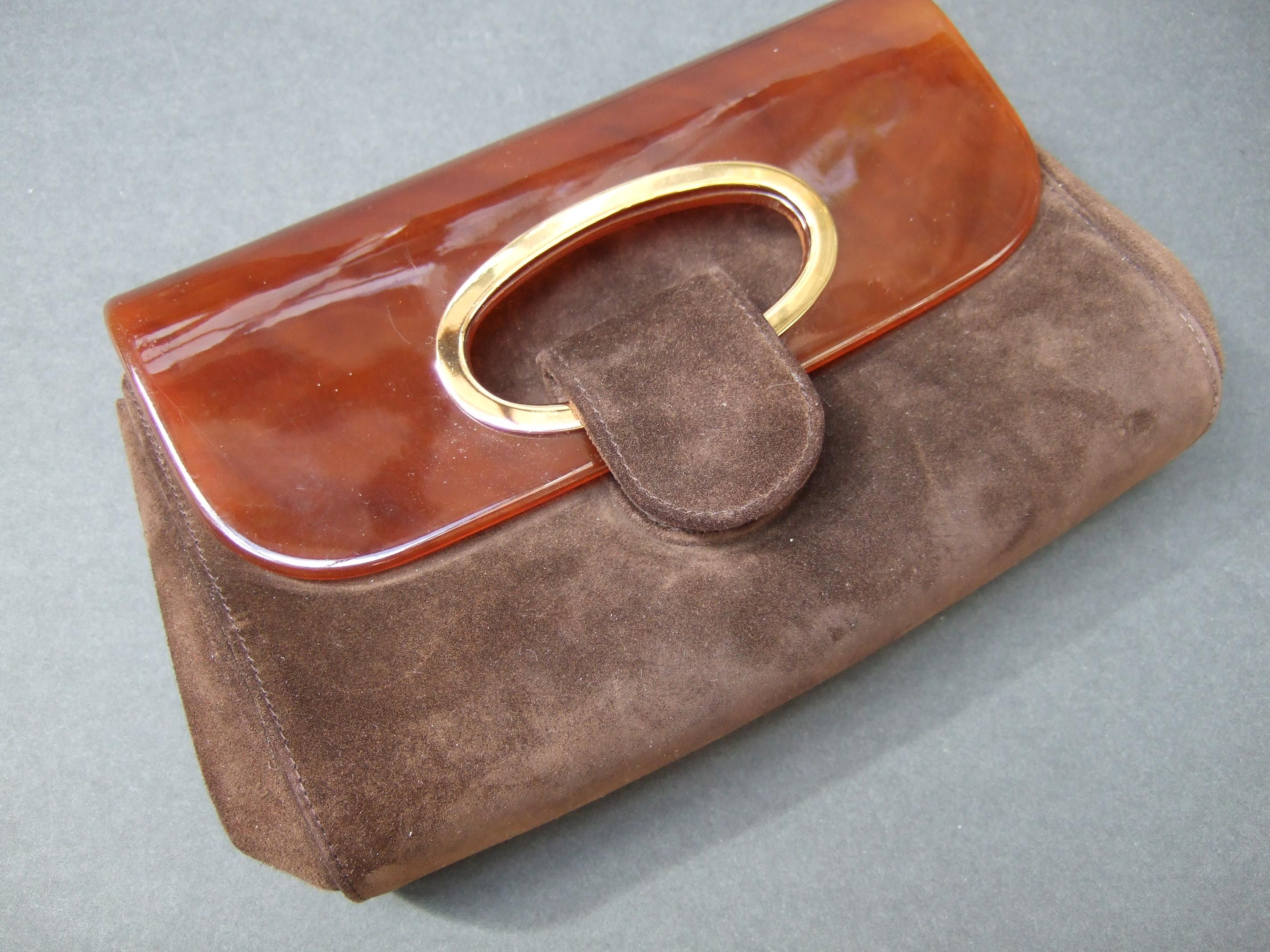 Gucci Italy Rare amber lucite brown suede clutch bag c 1970s
The unique Gucci clutch is designed with a sleek amber color lucite flap cover on the front exterior. The Italian clutch is covered with plush dark chocolate brown suede

The suede covered