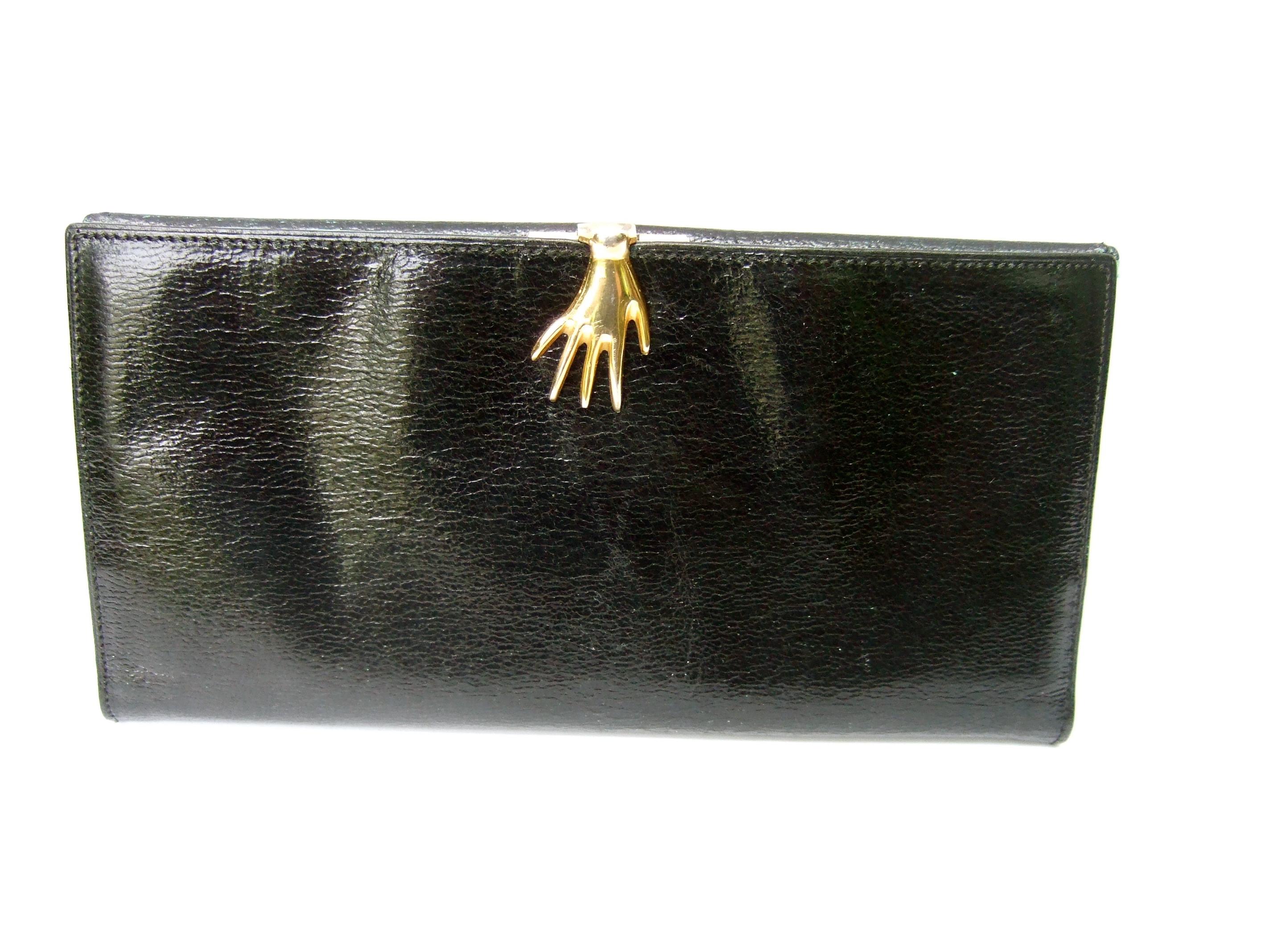 Gucci Italy Rare black leather hand clasp wallet c 1970s
The stylish Italian wallet is covered with smooth grainy black
leather with a sheen 

Adorned with a small gilt metal hand that serves as the clasp
mechanism. The interior is partially lined
