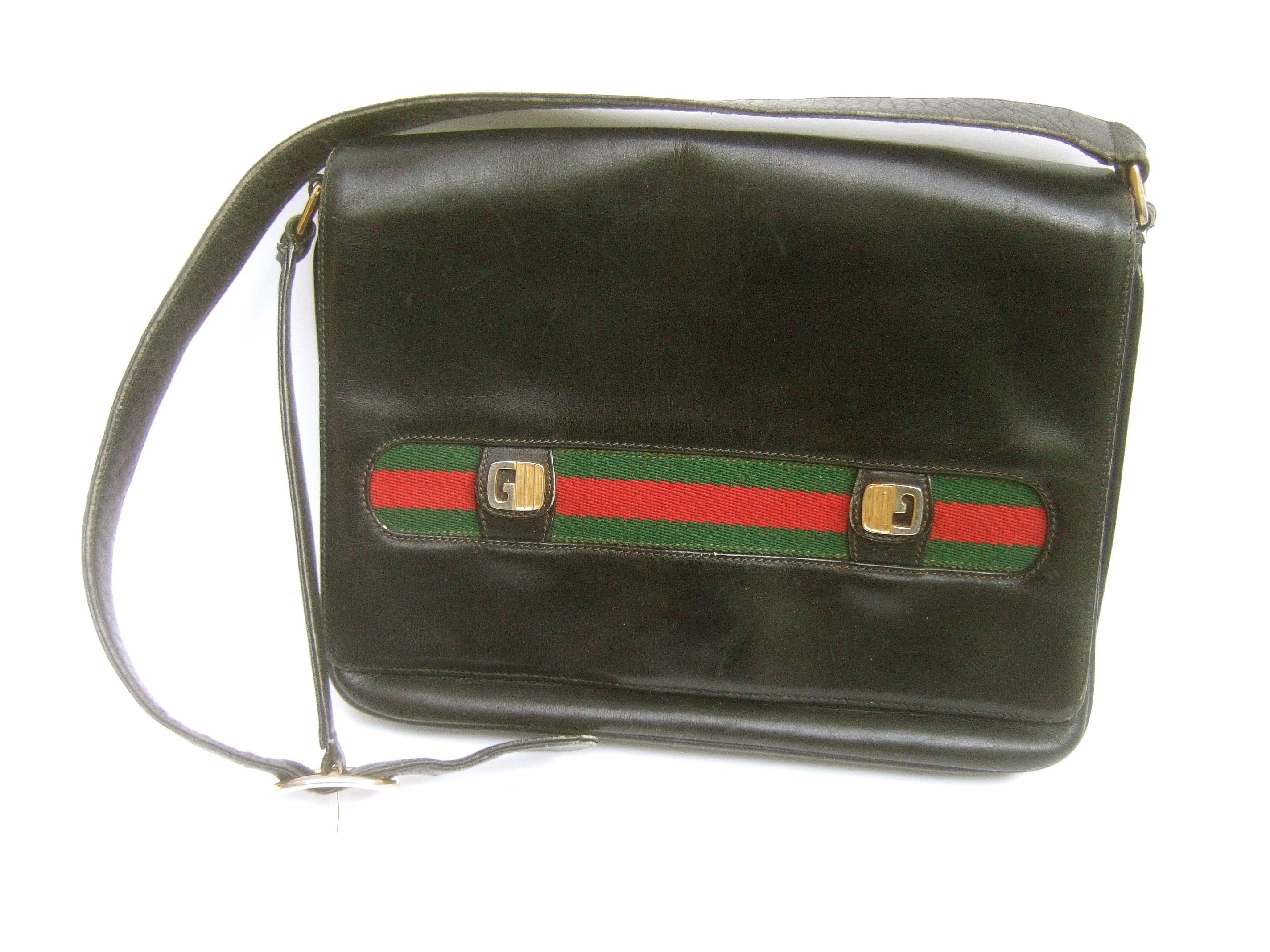 Gucci Italy Rare black leather webbed striped shoulder bag c 1970s 
The unique Gucci handbag is covered with smooth black leather 
The front flap cover is accented with Gucci's signature red & green
canvas webbed stripes. Adorned with Gucci's gilt