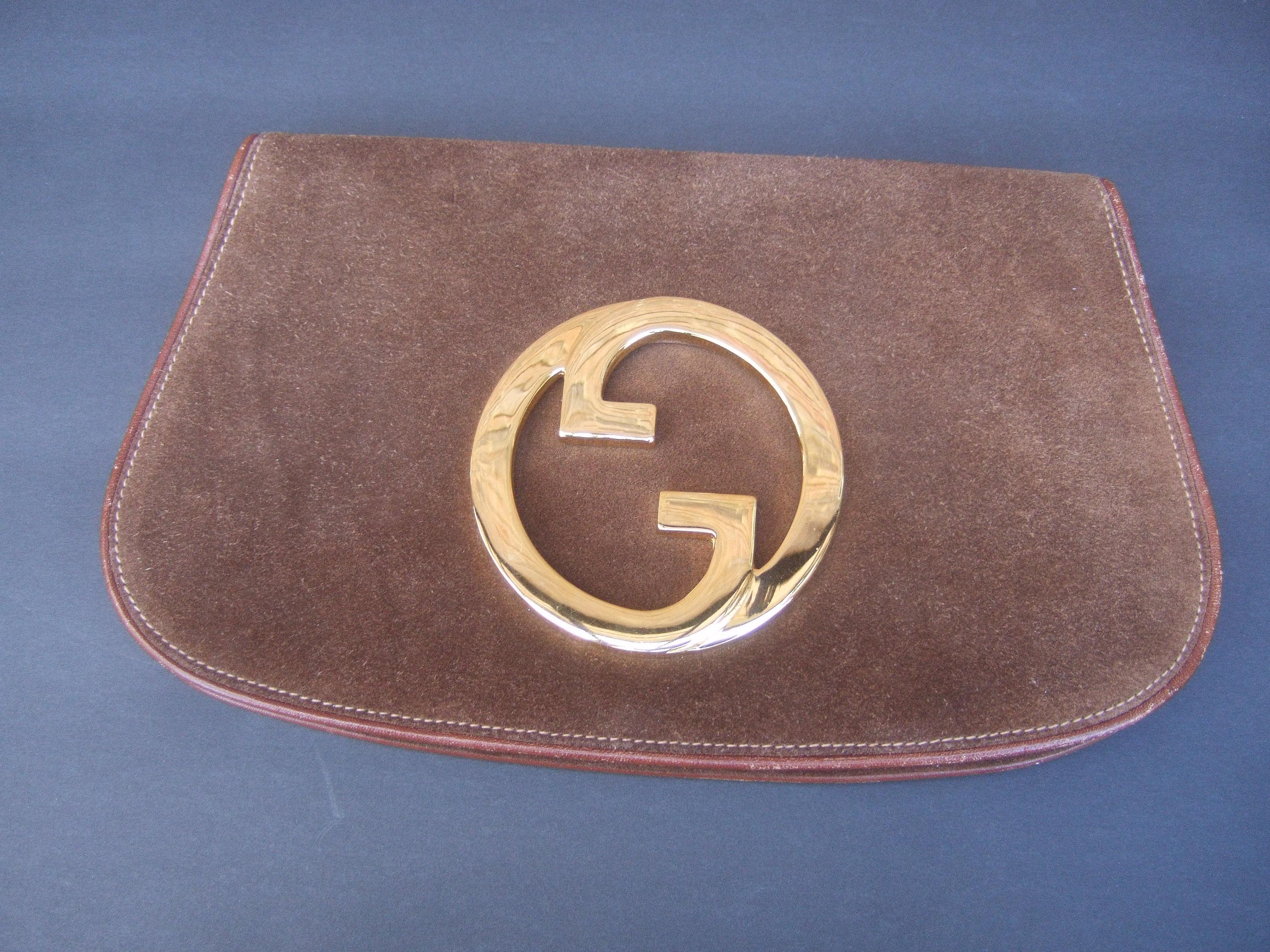 Gucci Italy Brown suede blondie clutch c 1970s
The rare Gucci clutch is covered with luxurious
chocolate brown suede

Adorned with Gucci's massive gilt metal interlocked 
G.G. initials. The interior is lined in tan suede designed 
with a slip pocket