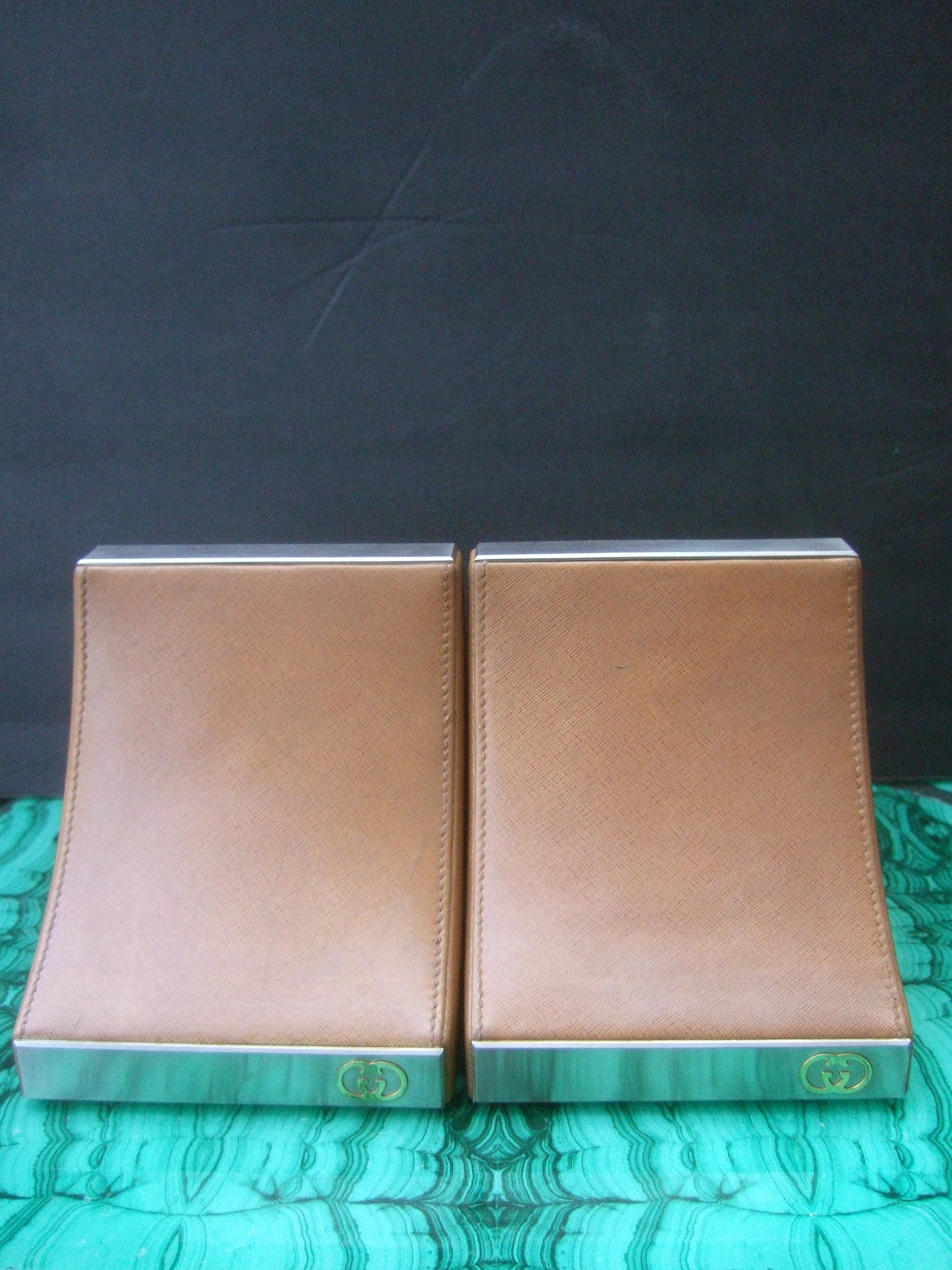 Gucci Italy Rare caramel brown leather pair of bookends c 1970s
The elegant pair of bookends are covered with smooth light brown leather
The front exterior base is designed with a rectangular silver metal plate 
with Gucci's understated interlocked