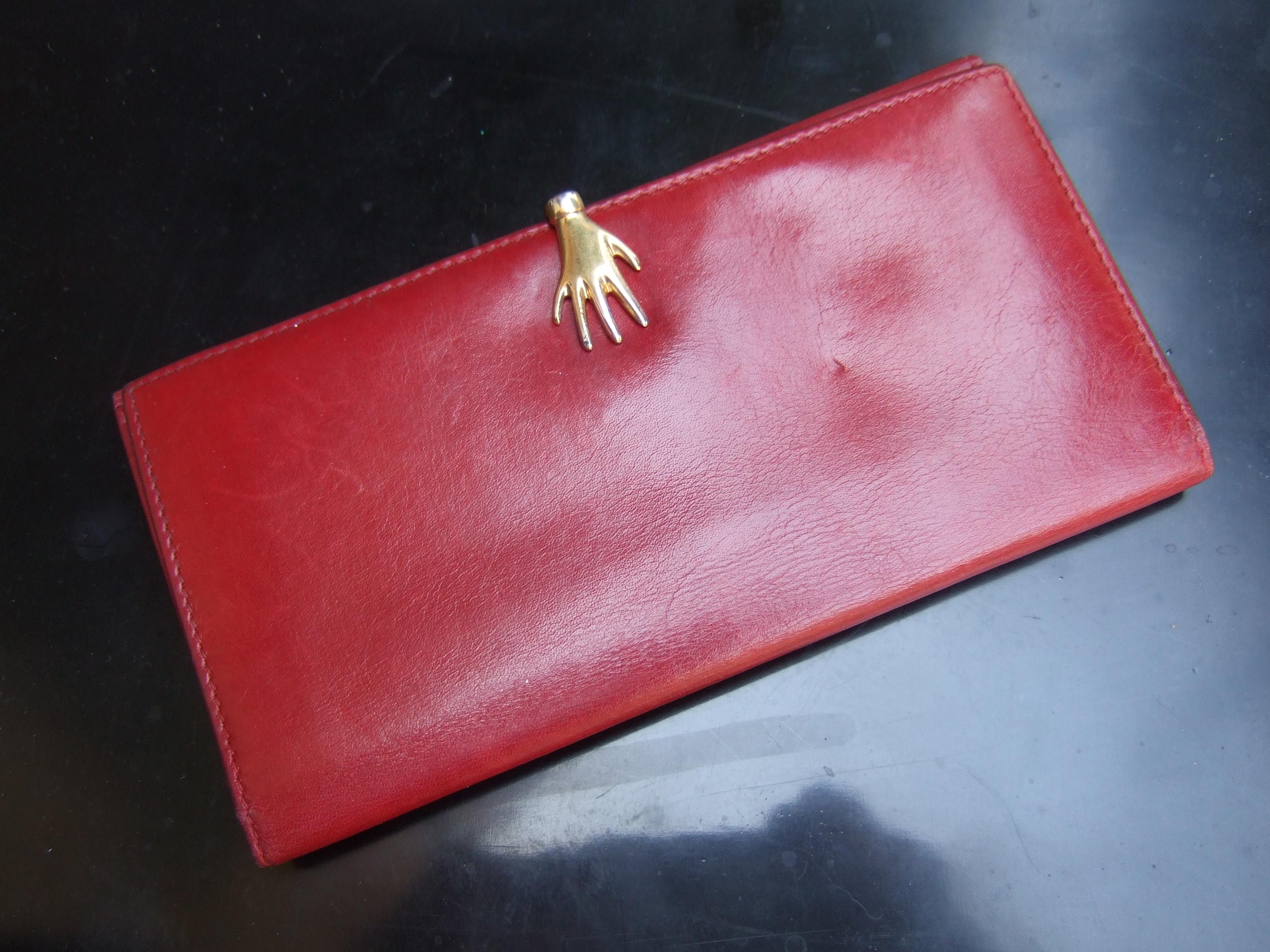 Gucci Italy Rare cherry red leather hand clasp wallet c 1980s
The stylish Italian wallet is designed with a unique gilt metal
hand that serves as the closure mechanism 

The interior is lined with smooth matching red leather designed
with six credit