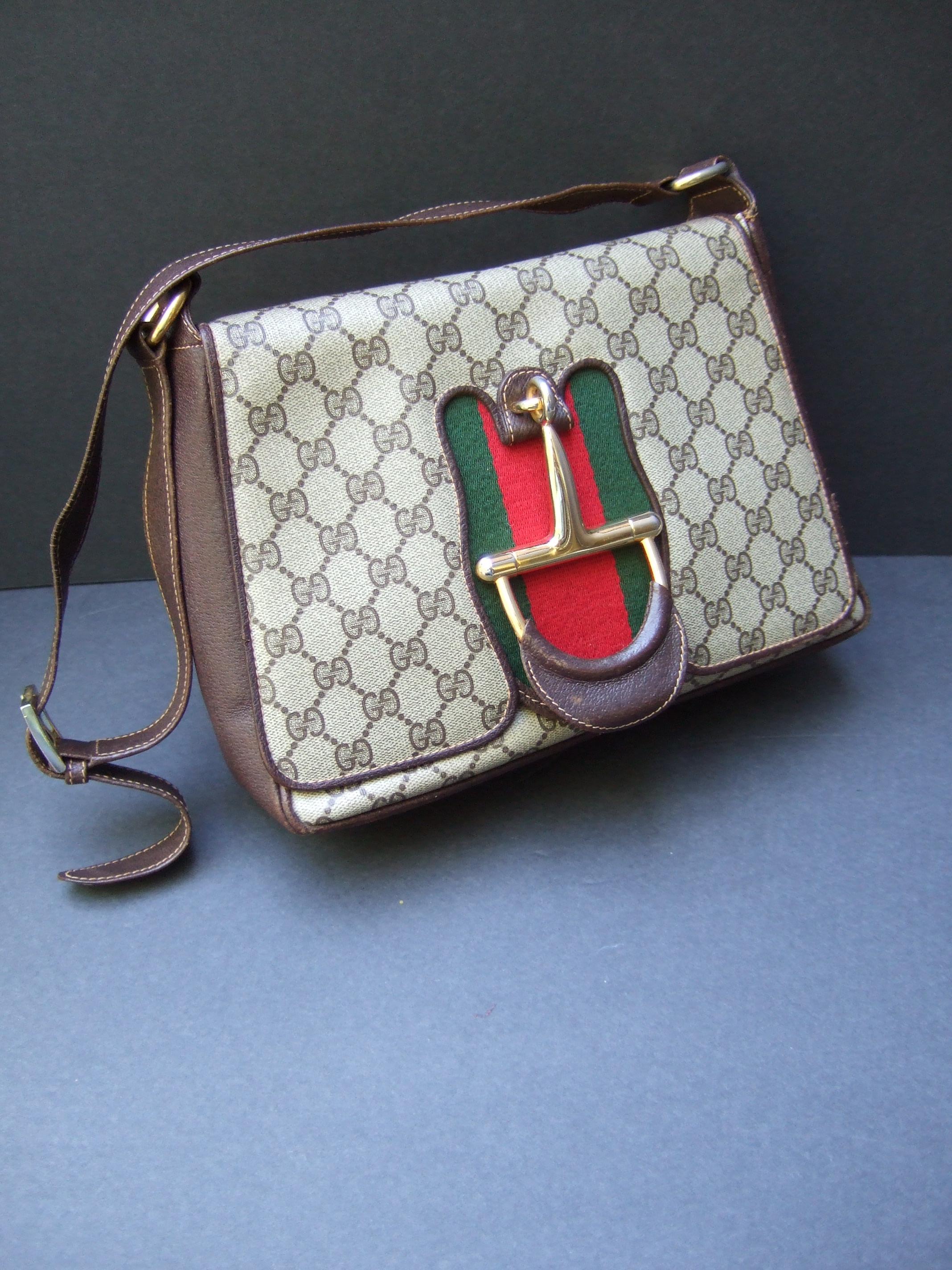 Gucci Italy Rare Gilt metal bridal medallion brown coated canvas shoulder bag c 1970s
The stylish Italian handbag is adorned with a huge scale gilt metal bridal medallion 
framed with Gucci's iconic red & green canvas webbed stripes 

The saddle