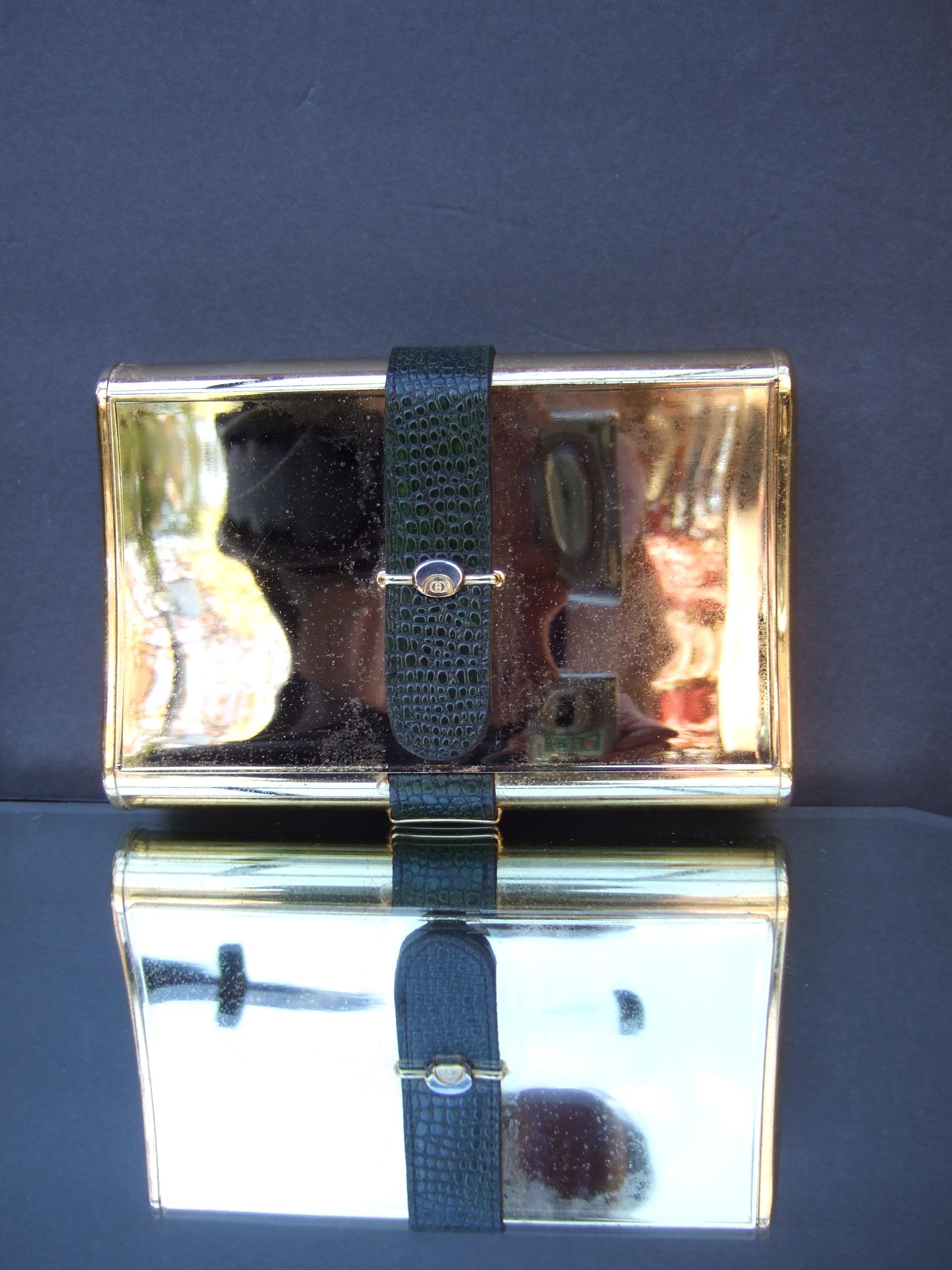 Gucci Italy Rare opulent gold plated minaudiere' clutch c 1970s
The elegant gold metal clutch is designed with a green leather embossed band 
that runs vertically across the center of the hinged lid cover & extends to the back exterior

Gucci's