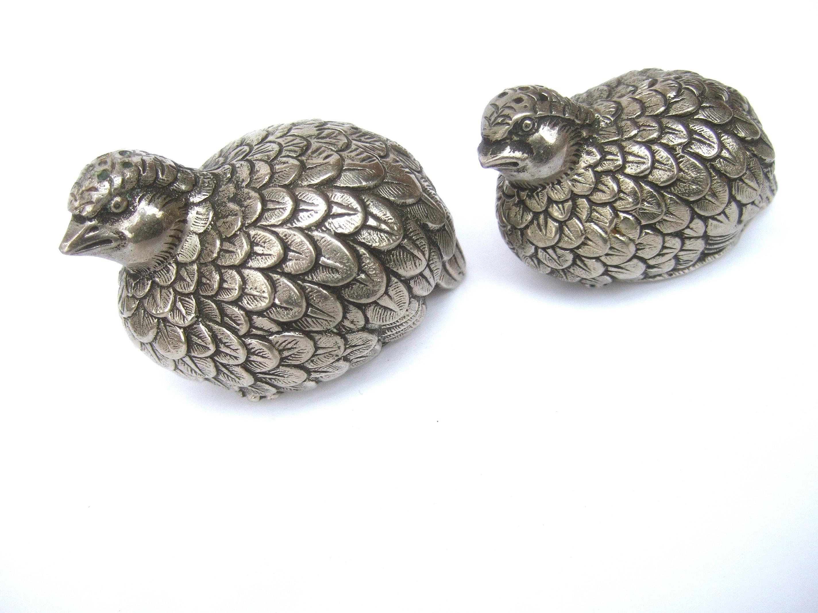 Gucci Italy Rare silver metal quail salt & pepper shakers c 1970s
The elegant quail figures are designed with silver plated textured
metal with intricate detail that emulates their plumage  

The pair of quail figures make elegant fine dining decor
