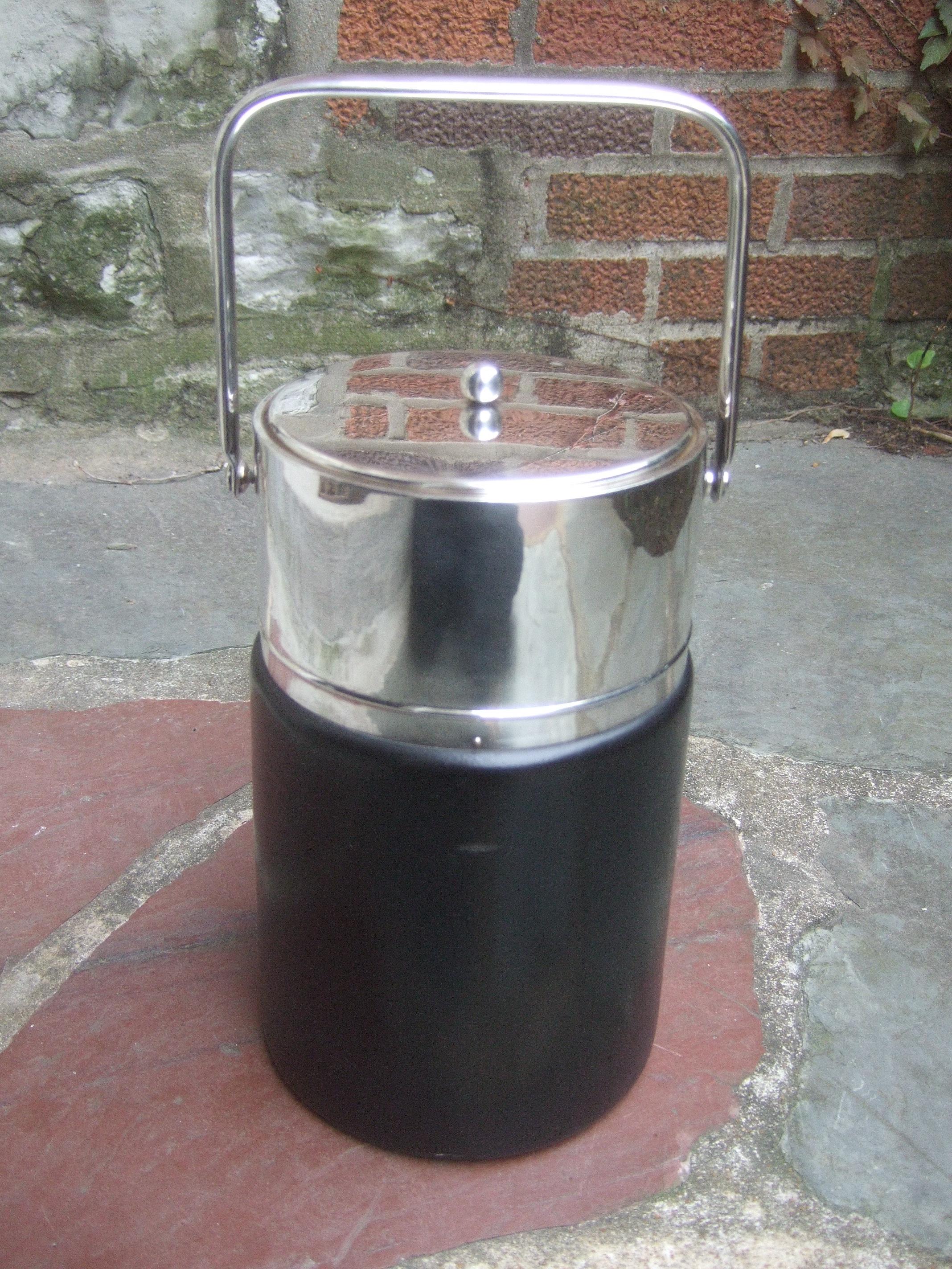 Gucci Italy Sleek chrome black leather ice bucket c 1970s 
The stylish Italian ice bucket is designed with a chrome metal lid, swivel handle and a wide chrome band that circles the upper section of the ice bucket

The mid-section and lower section
