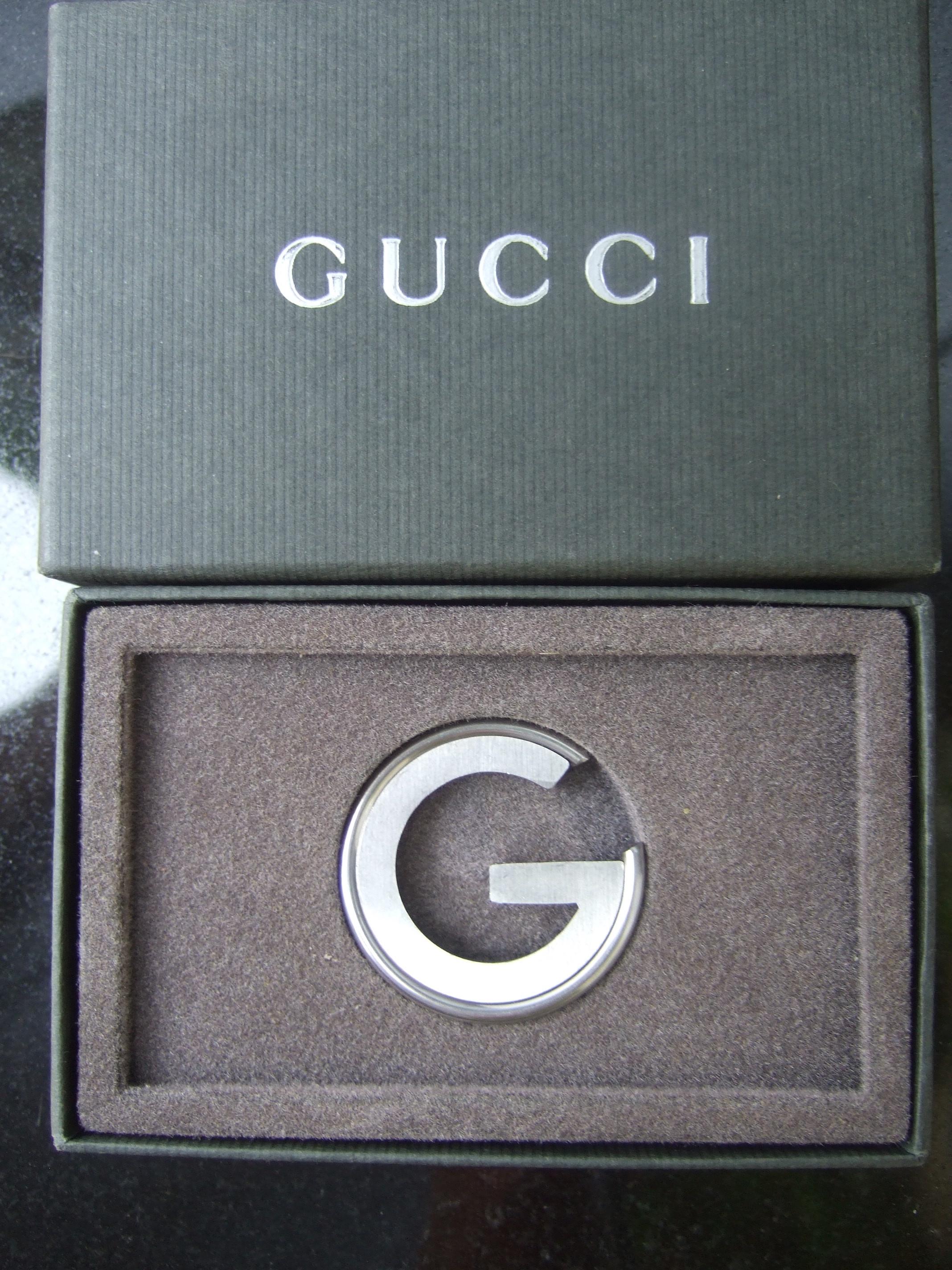 Gucci Italy small round book mark / desk collectible in Gucci presentation box  21st c. Tom Ford era 
The small silver metal G medallion may serve as a bookmark placed inside a book
It too makes a stylish small size desk collectible 

Paired with