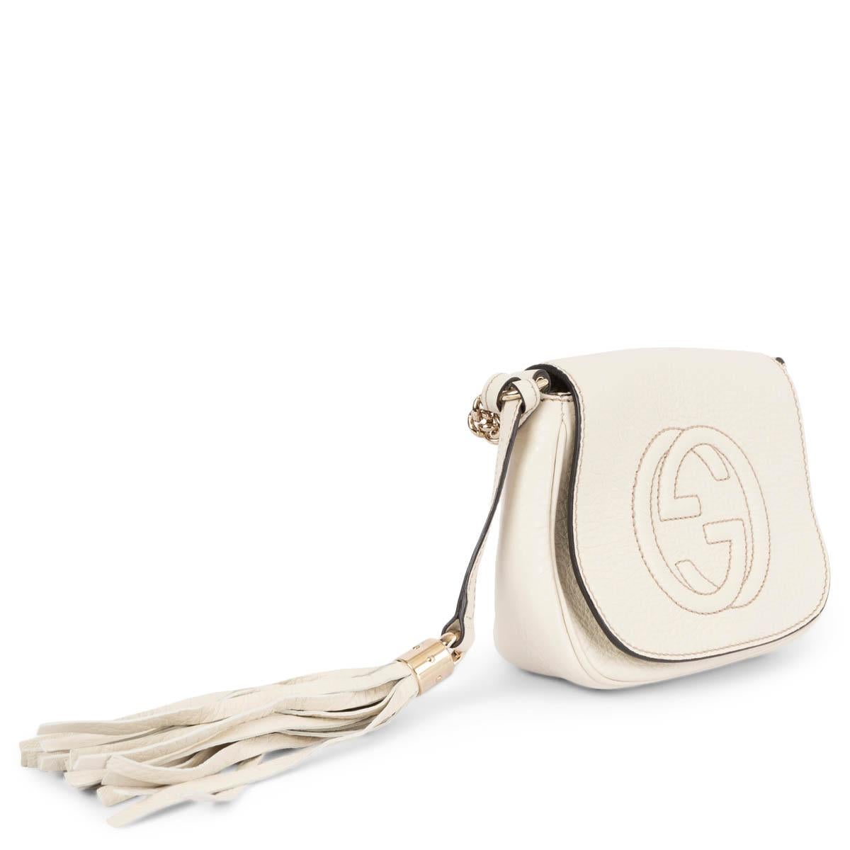 100% authentic Gucci Small Soho flap crossbody bag in ivory peppled calfskin leather. Features a debossed GG logo on the front, a tassel and light gold-tone chain. Opens with a magnetic button under the flap and is lined in off-white canvas with one