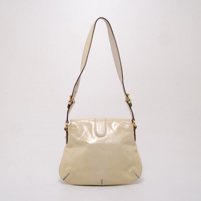 Add a dressy finish to your outfit with this Ivory Patent Wave shoulder bag by Gucci. Made from patent white leather, it is accented with luxe gold horsebit detailing and a shoulder strap. Its cozy interior is lined with lovely Gucci printed canvas