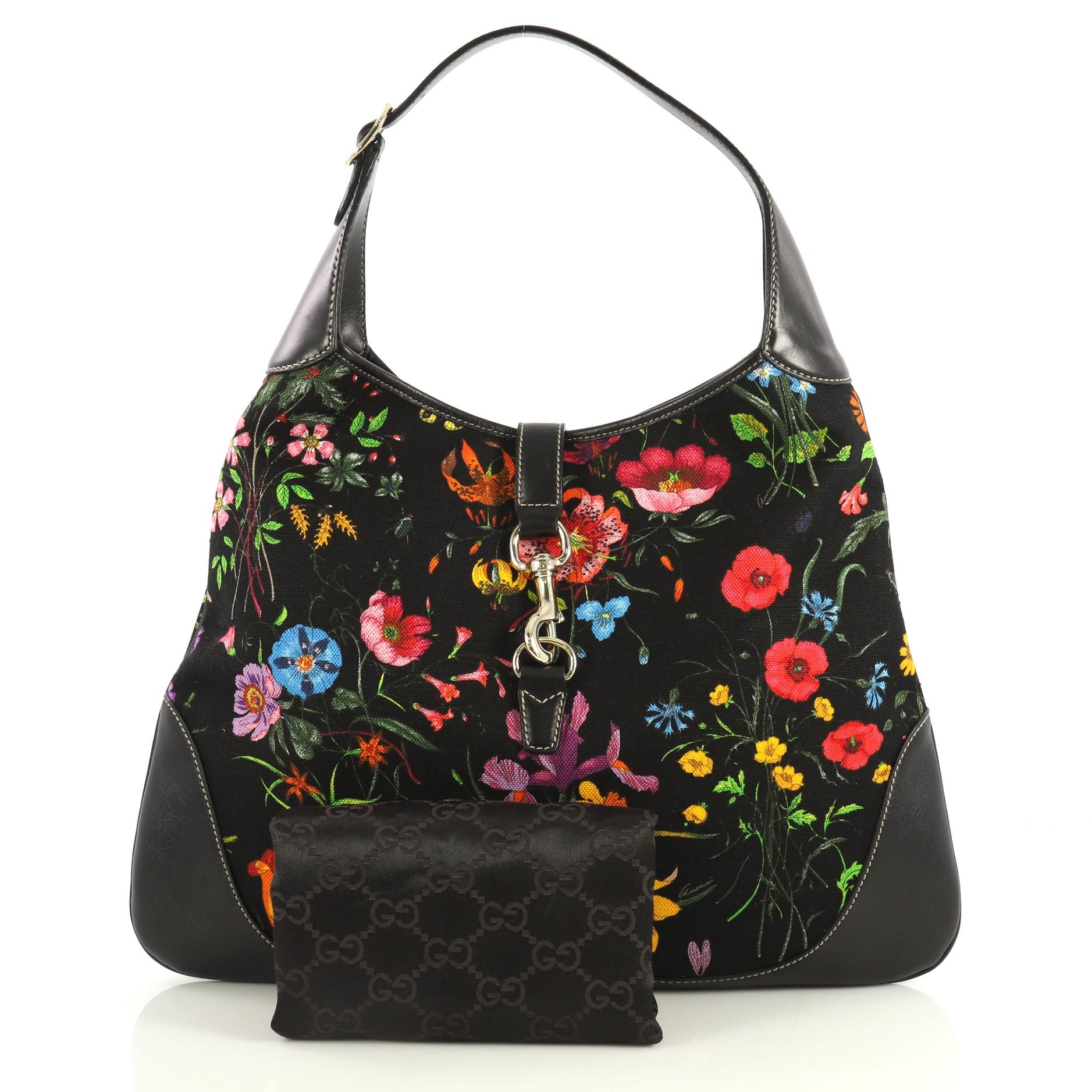 This Gucci Jackie O Bag Flora Canvas Large, crafted from black flora printed canvas, features an adjustable shoulder strap and gold-tone hardware. Its clip lock closure opens to a neutral canvas interior with side zip and slip pockets. 

Estimated